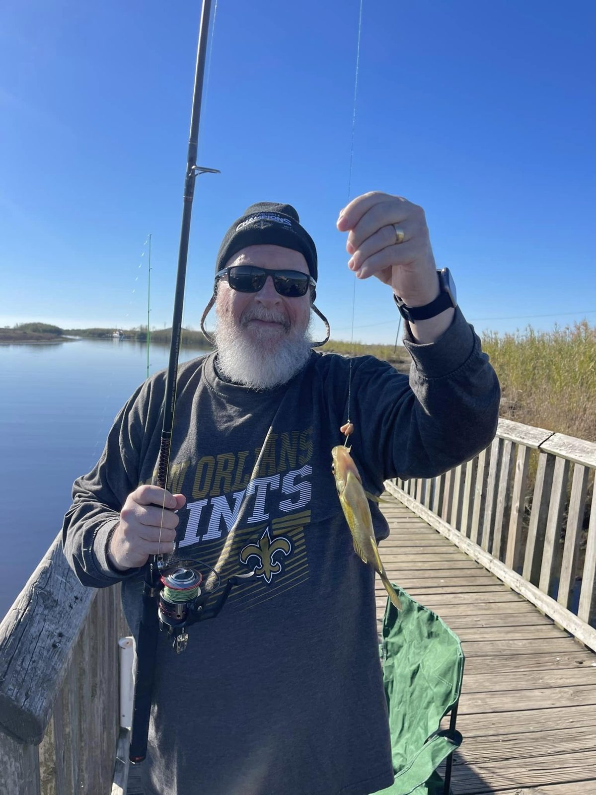 Danny holding up his catch beside the water