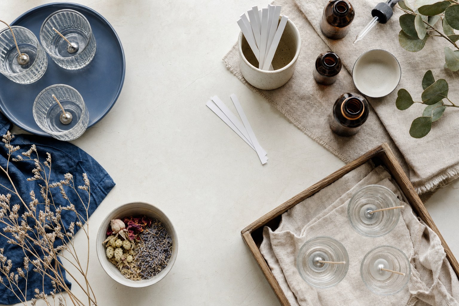 Candle vessels, scent bottles and botanical materials arranged for a candle-making party