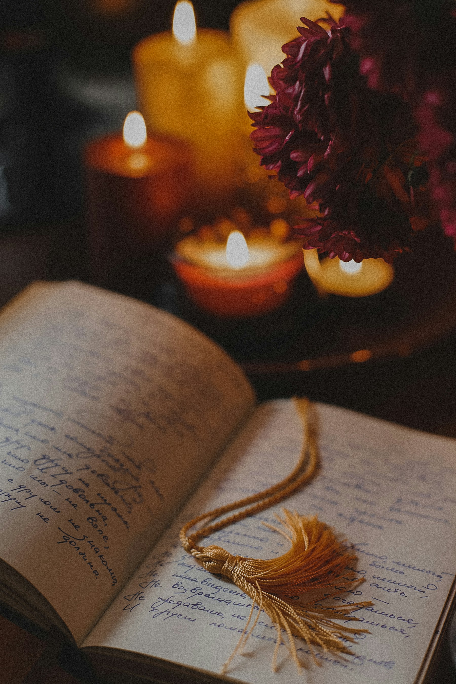 Open journal, candle, and red flowers in warm light