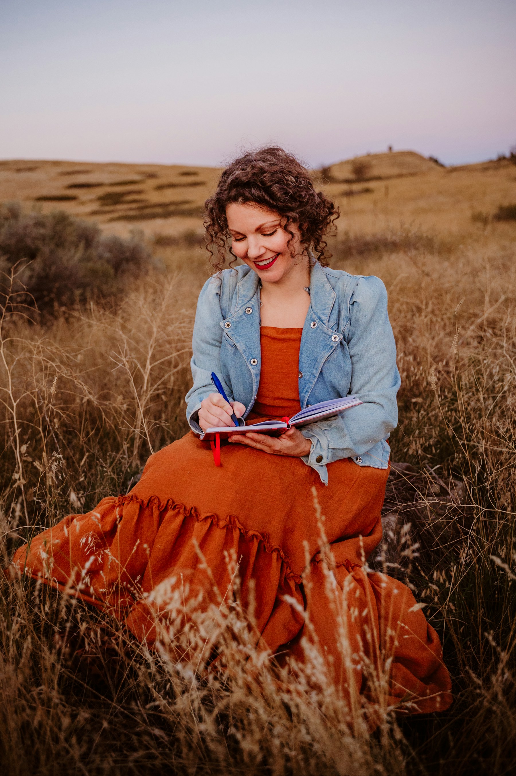 Woman writing in a journal in a sunlit meadow
