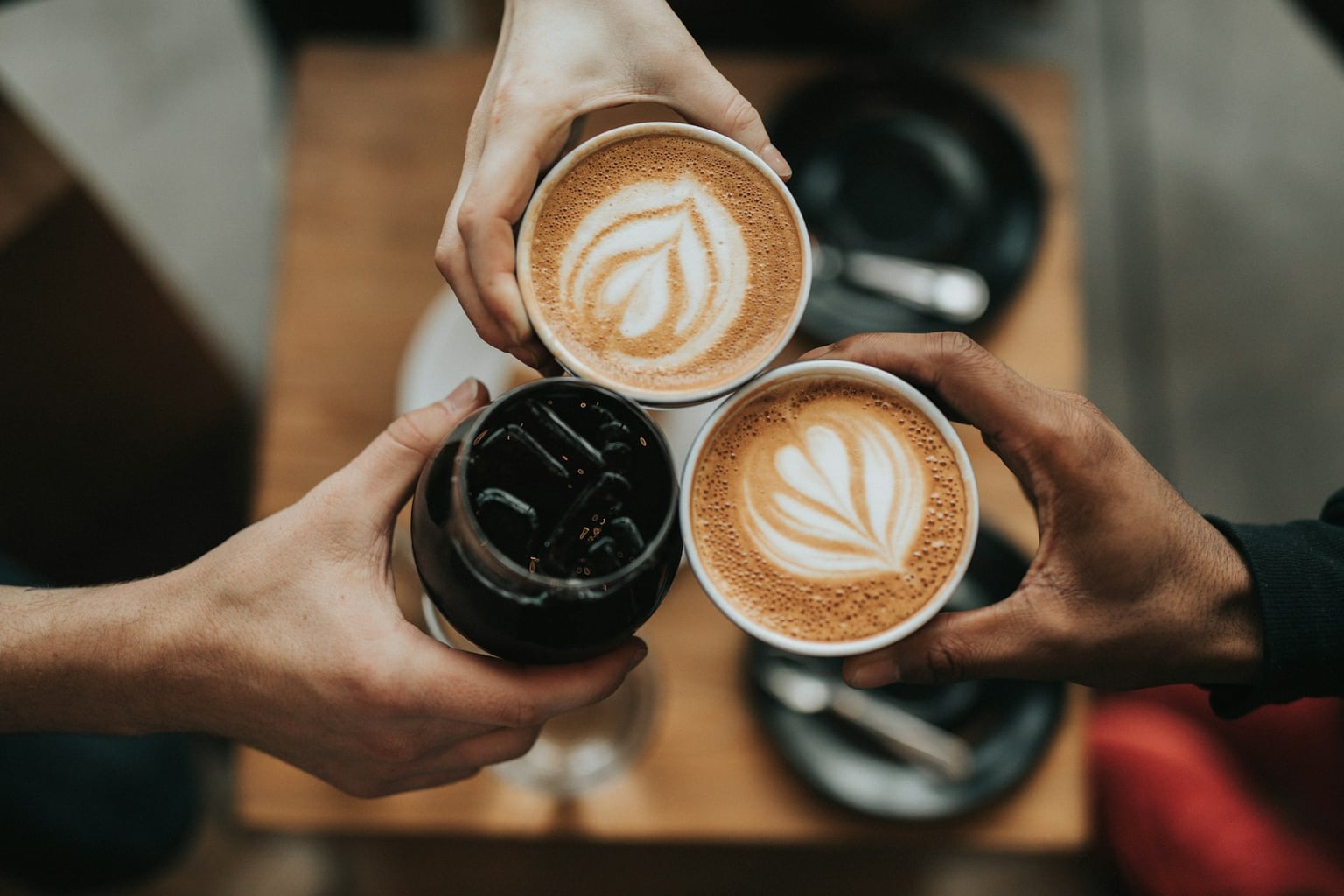 Three cups of coffee held together above a cafe table