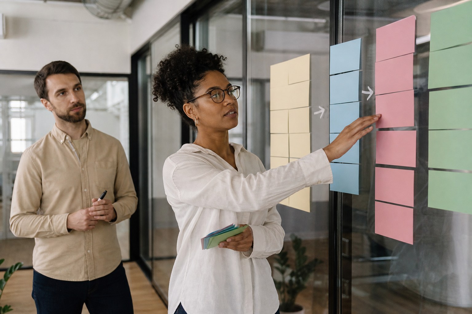Project coordinator mapping handoffs with color-coded cards on a glass wall