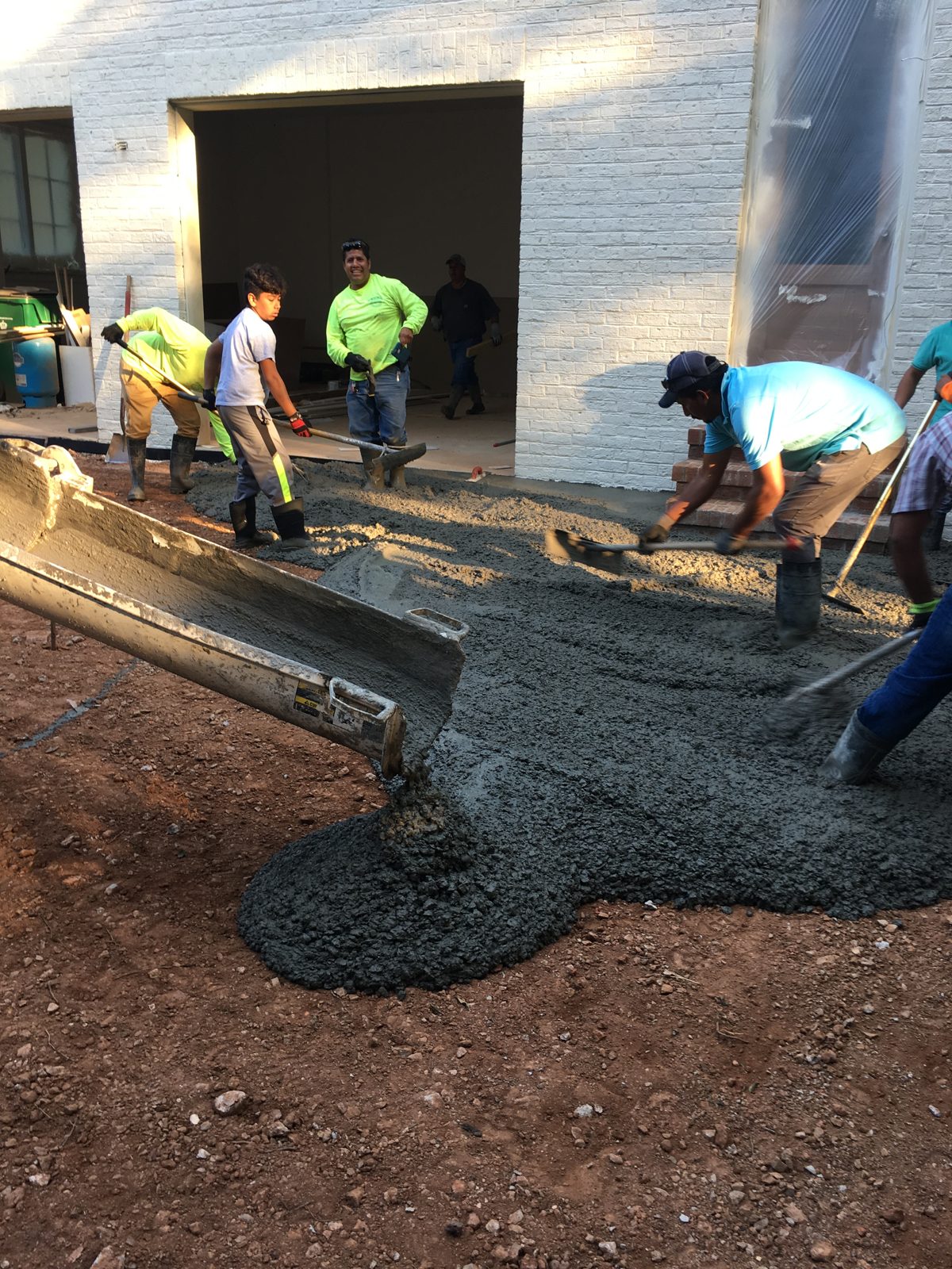 Concrete crew pouring a slab at a garage entrance