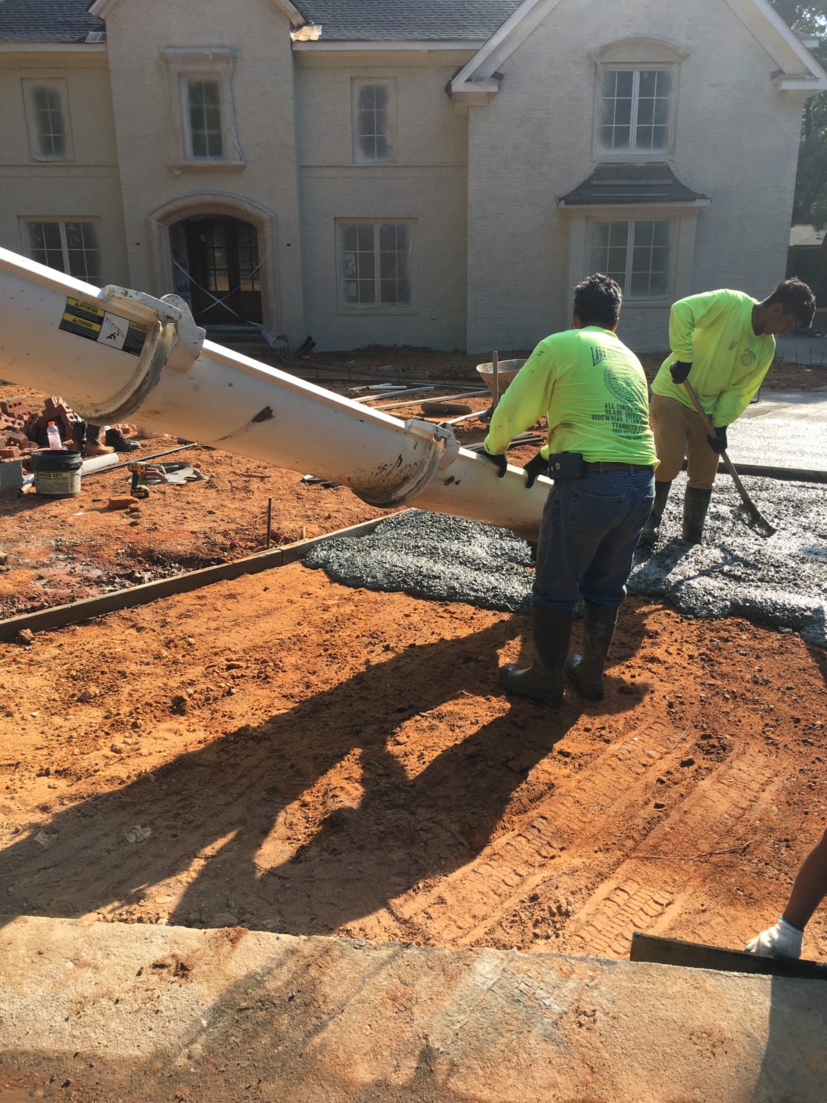 Crew placing fresh concrete beside a home using a truck chute