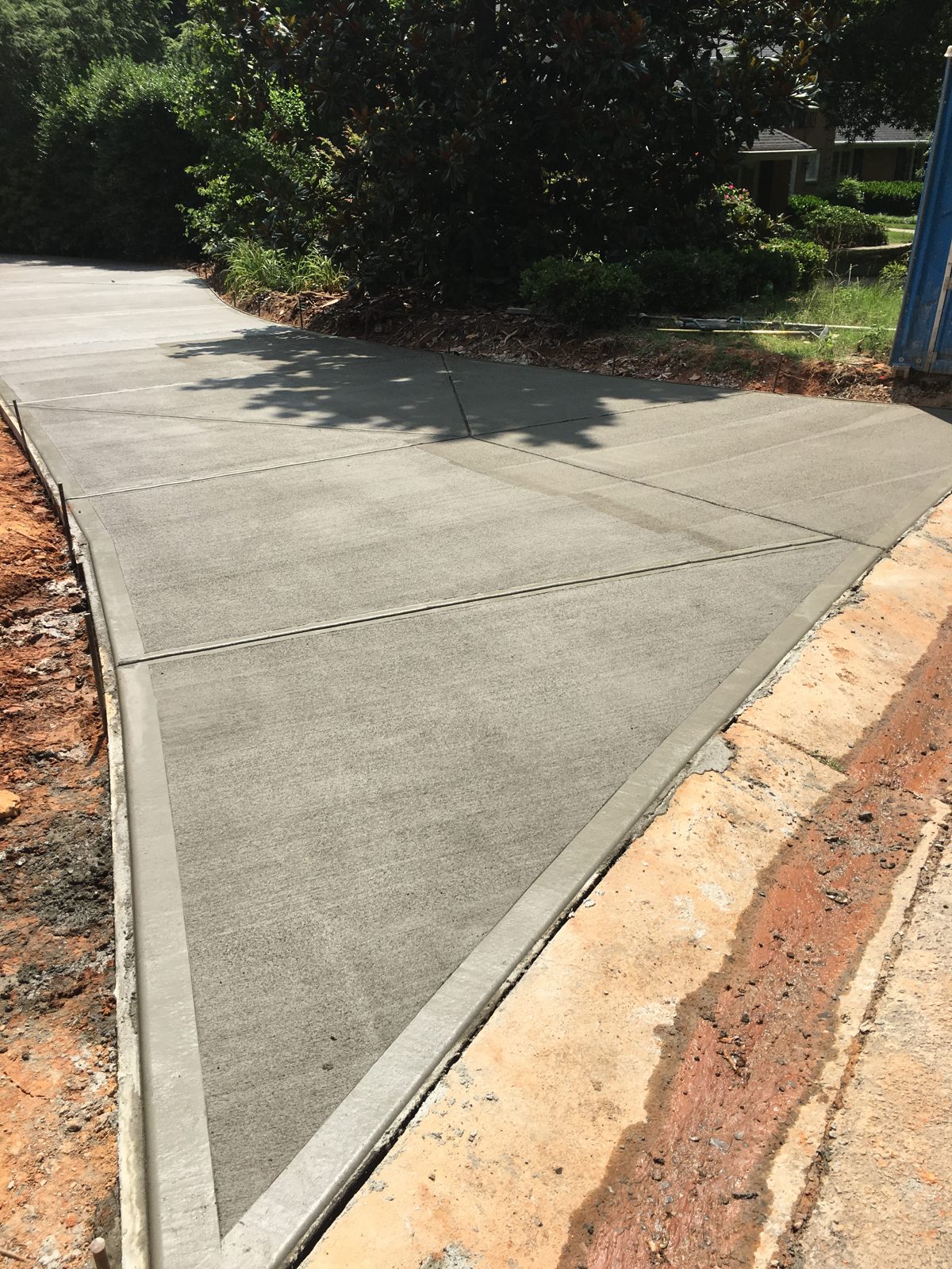 Curved concrete driveway edge beside prepared soil