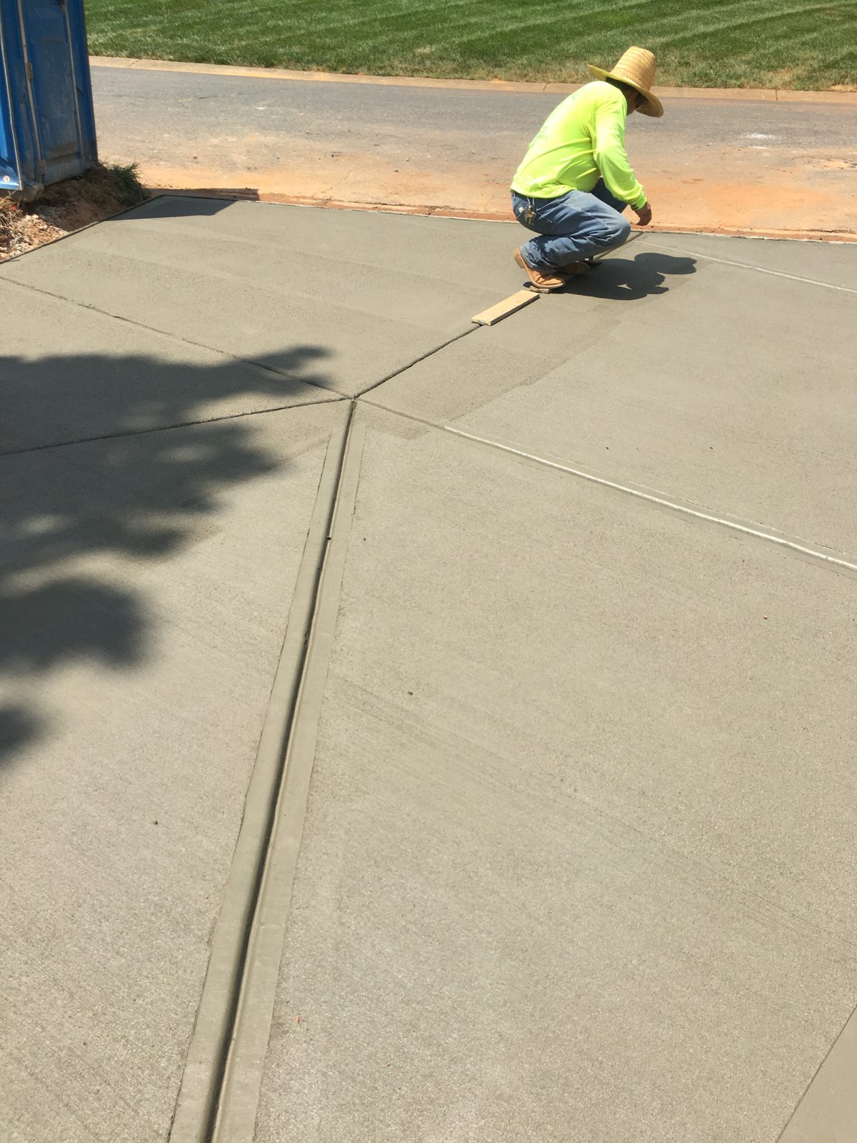 Concrete finisher working by hand along the edge of a fresh surface