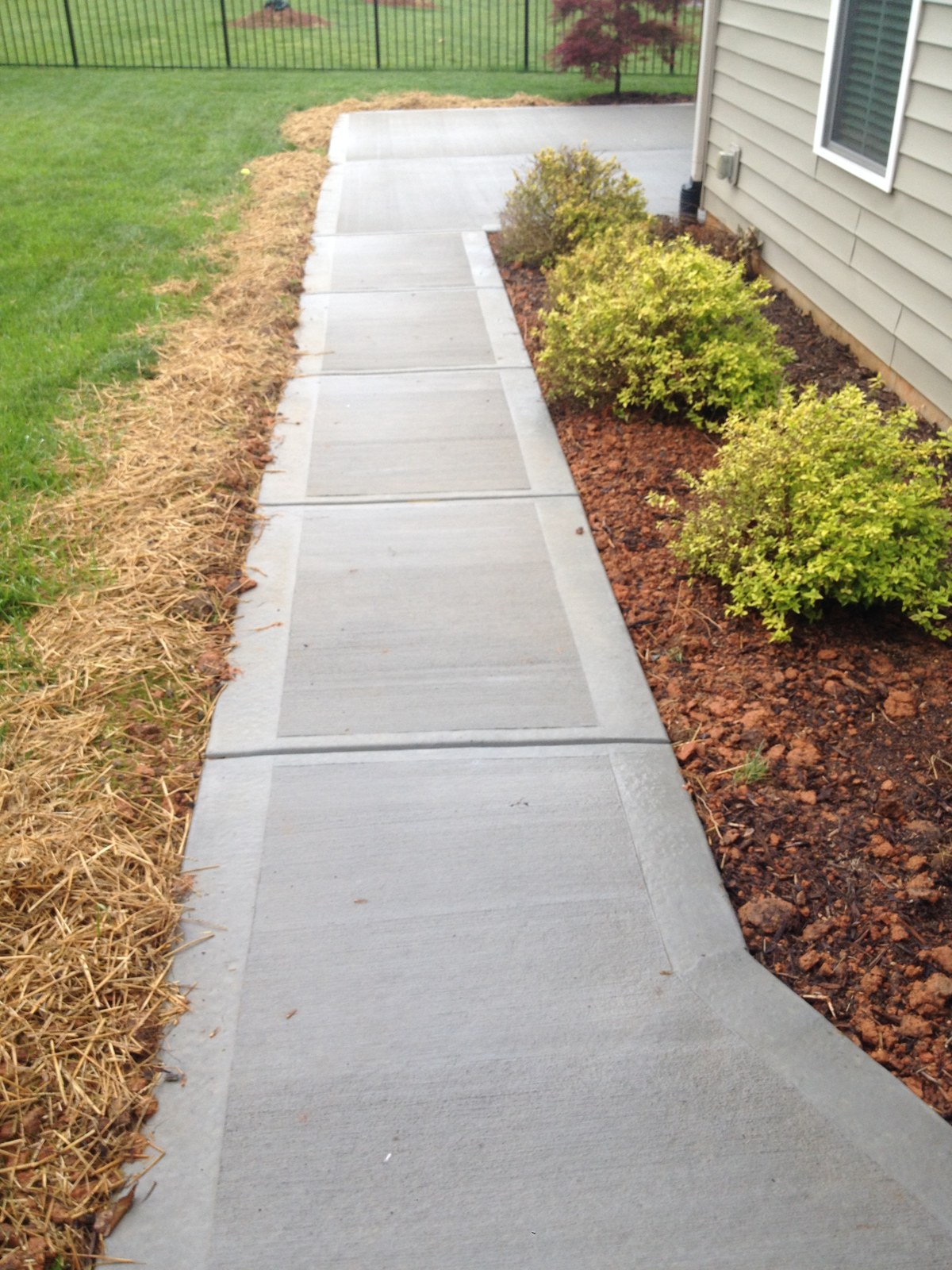 Finished residential concrete walkway beside a home