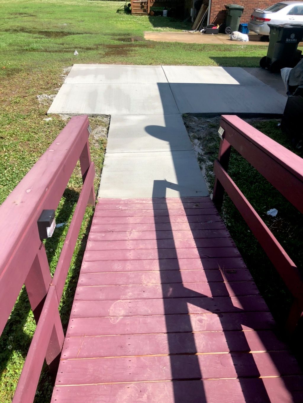 Concrete walkway connecting a wooden ramp to the yard