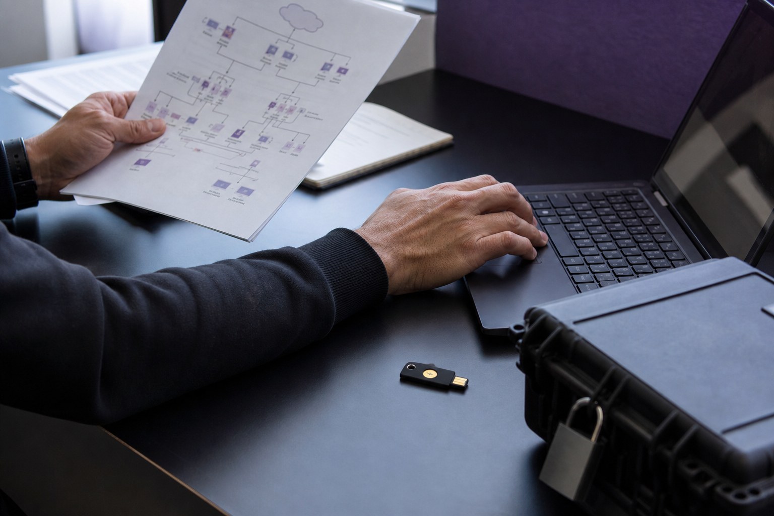 IT professional reviewing security documentation beside a laptop and security key