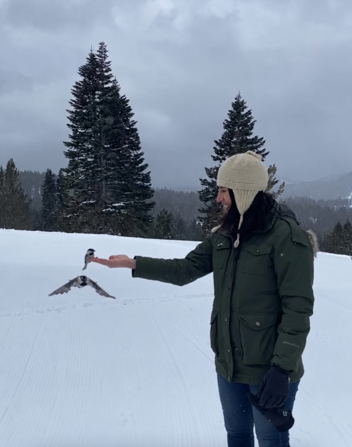 Avigail Schotz feeding a bird in a snowy landscape