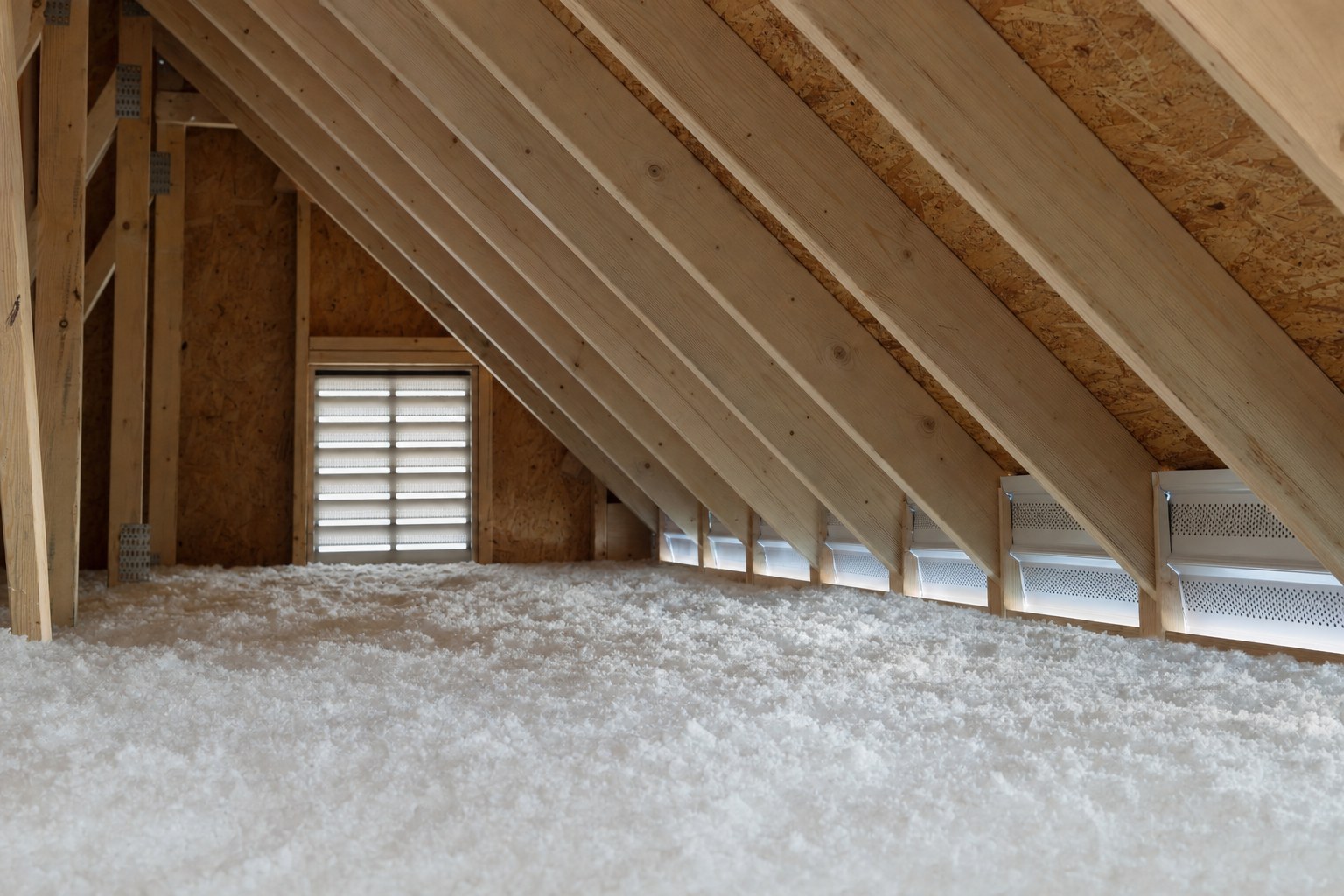 Attic insulation and soffit baffles below a sloped roof