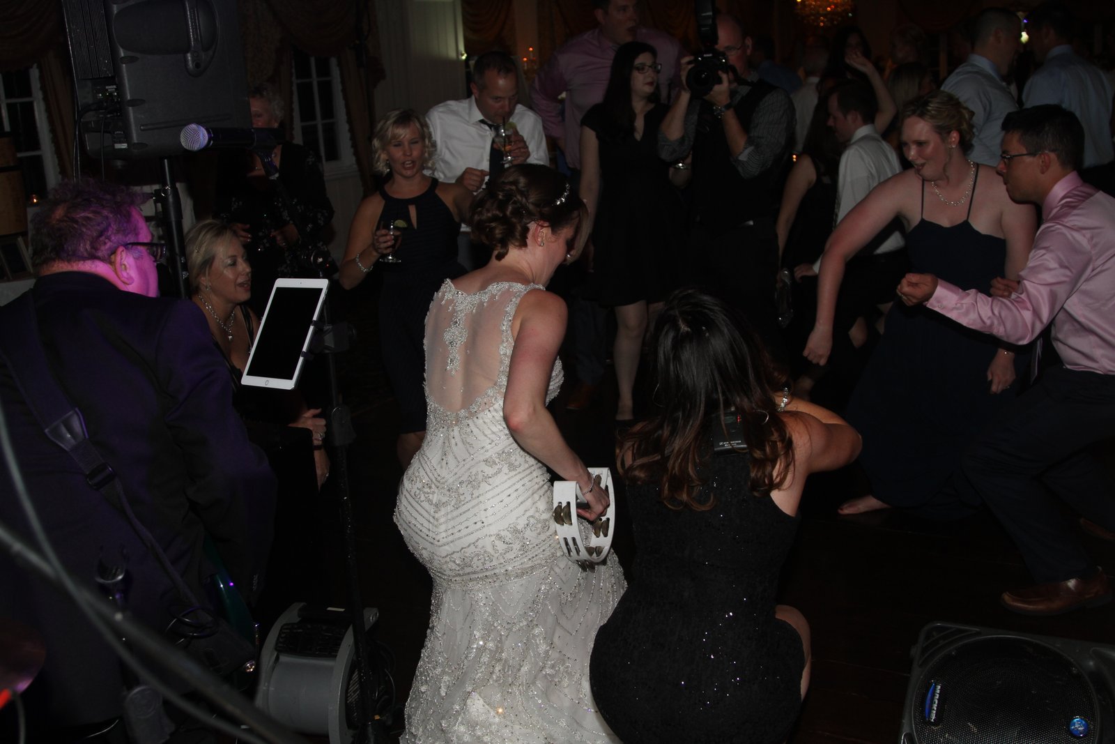 A bride playing tambourine as Bigg Romeo performs among wedding guests