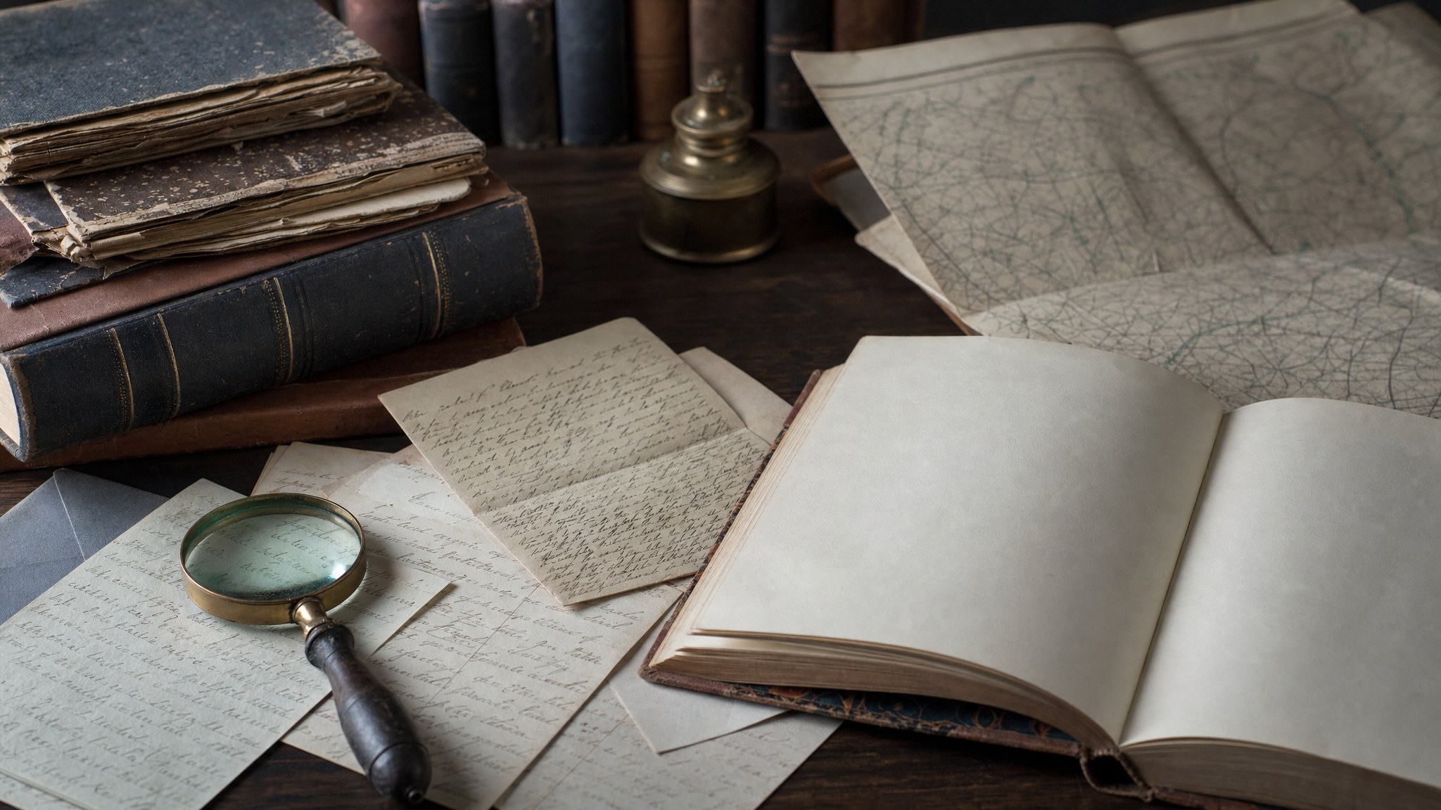 Archival-style correspondence, an open book, magnifying glass, and folded map on a library table
