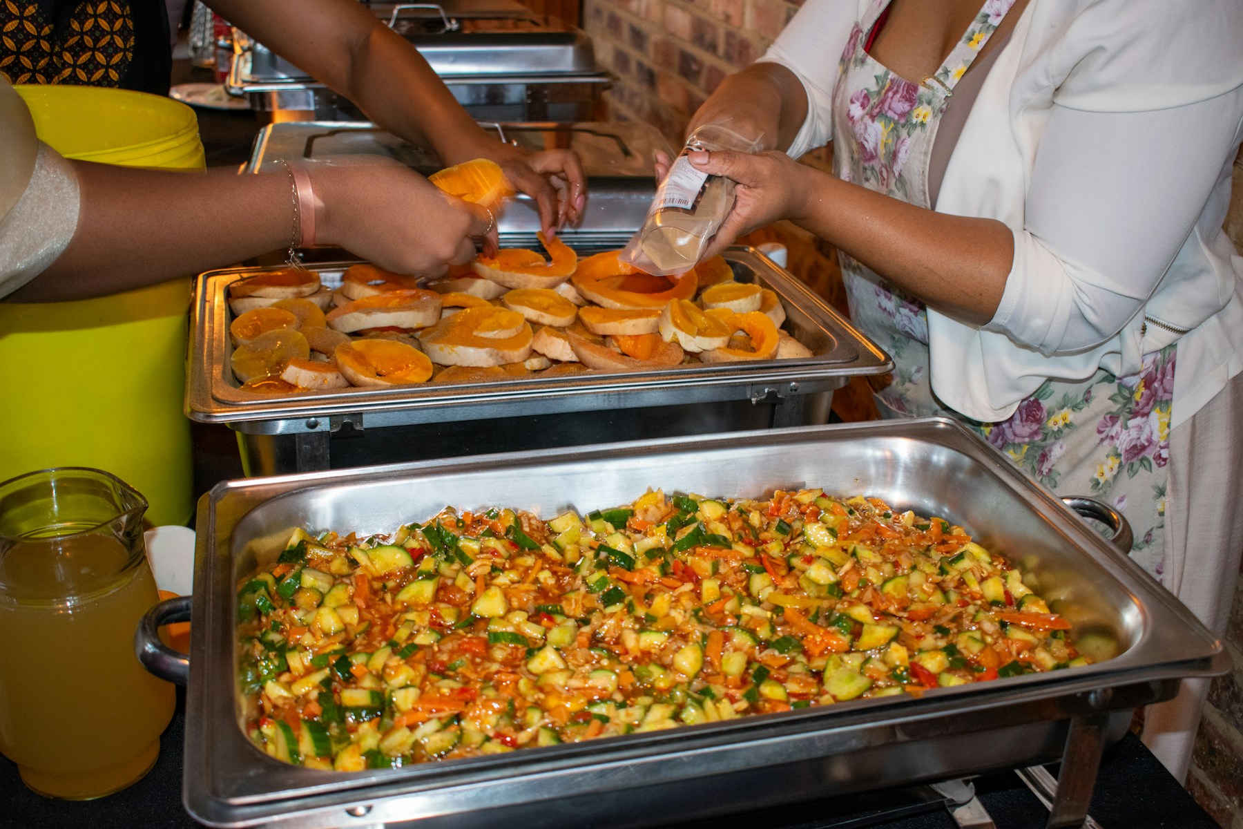 Catering staff serving food from chafing dishes at an event buffet