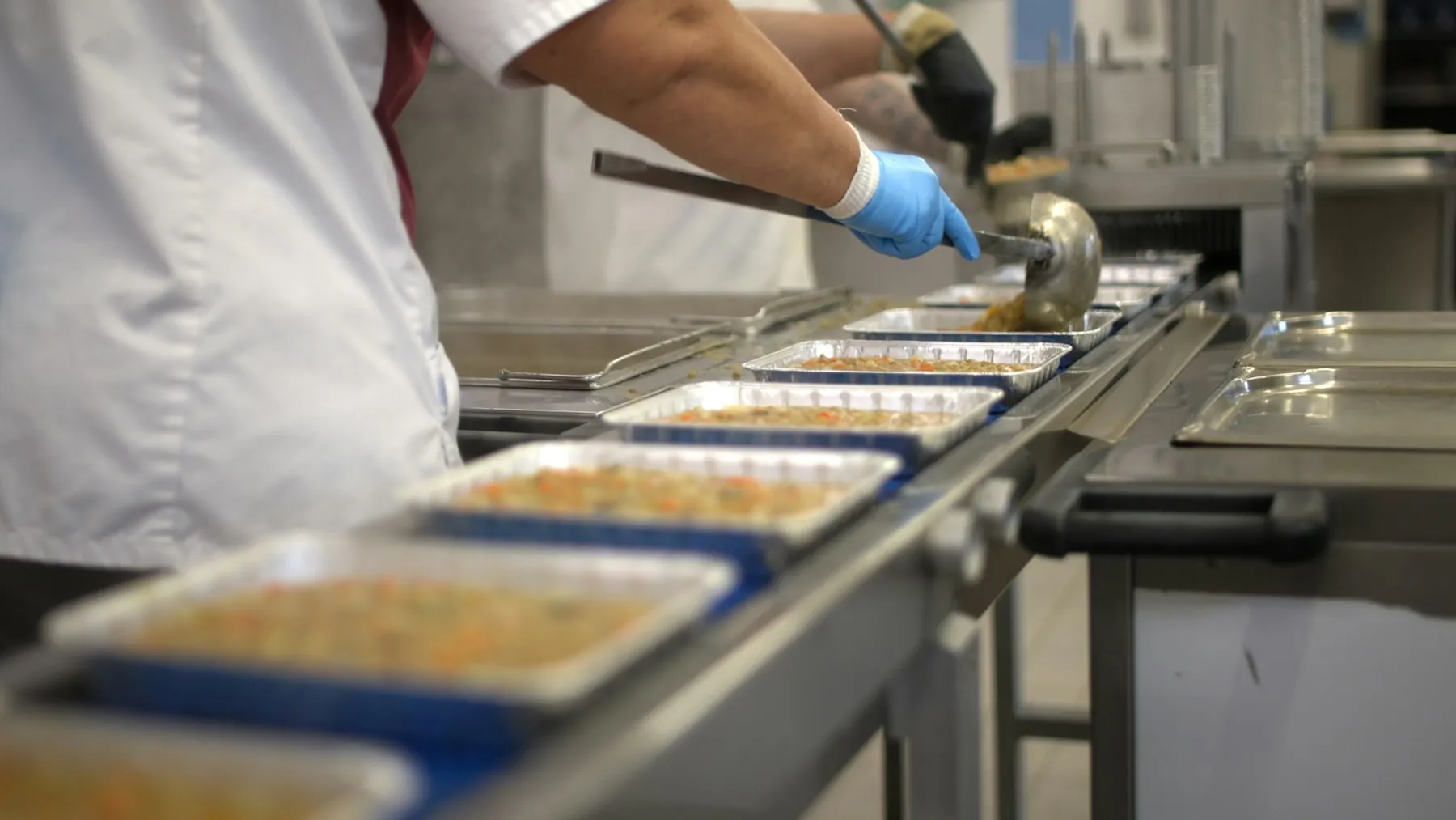 Catering owner reviewing event preparations beside insulated food carriers in a commercial kitchen