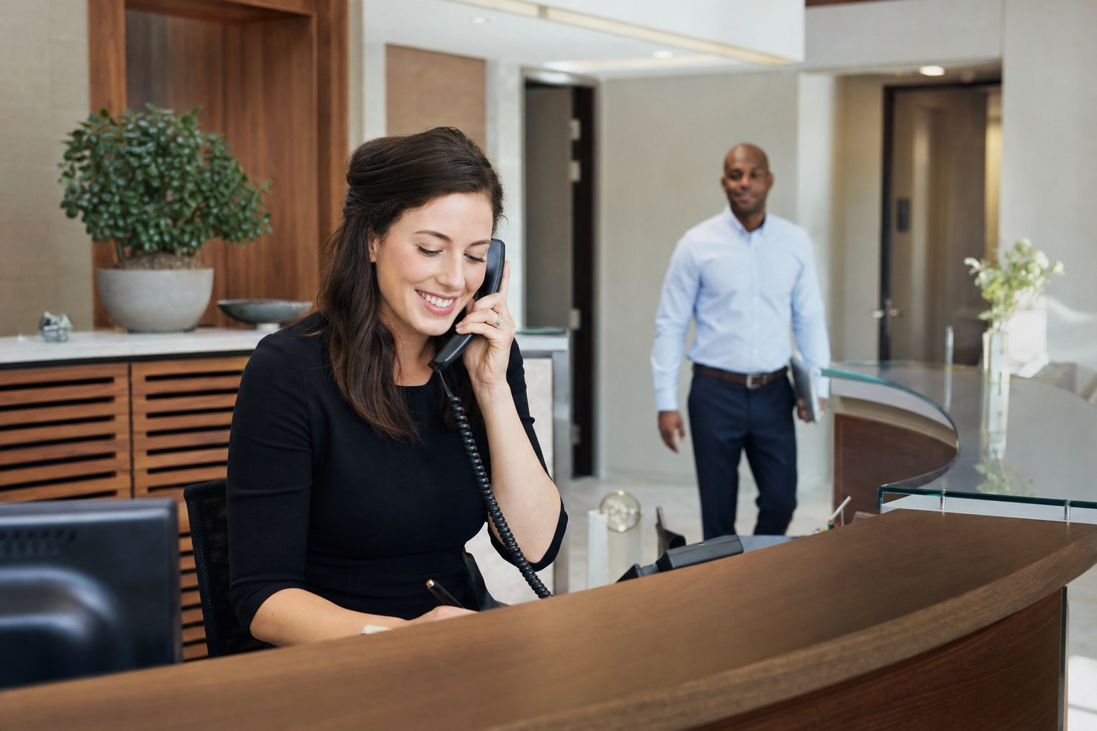 Receptionist handling a business call while a colleague is available for handoff