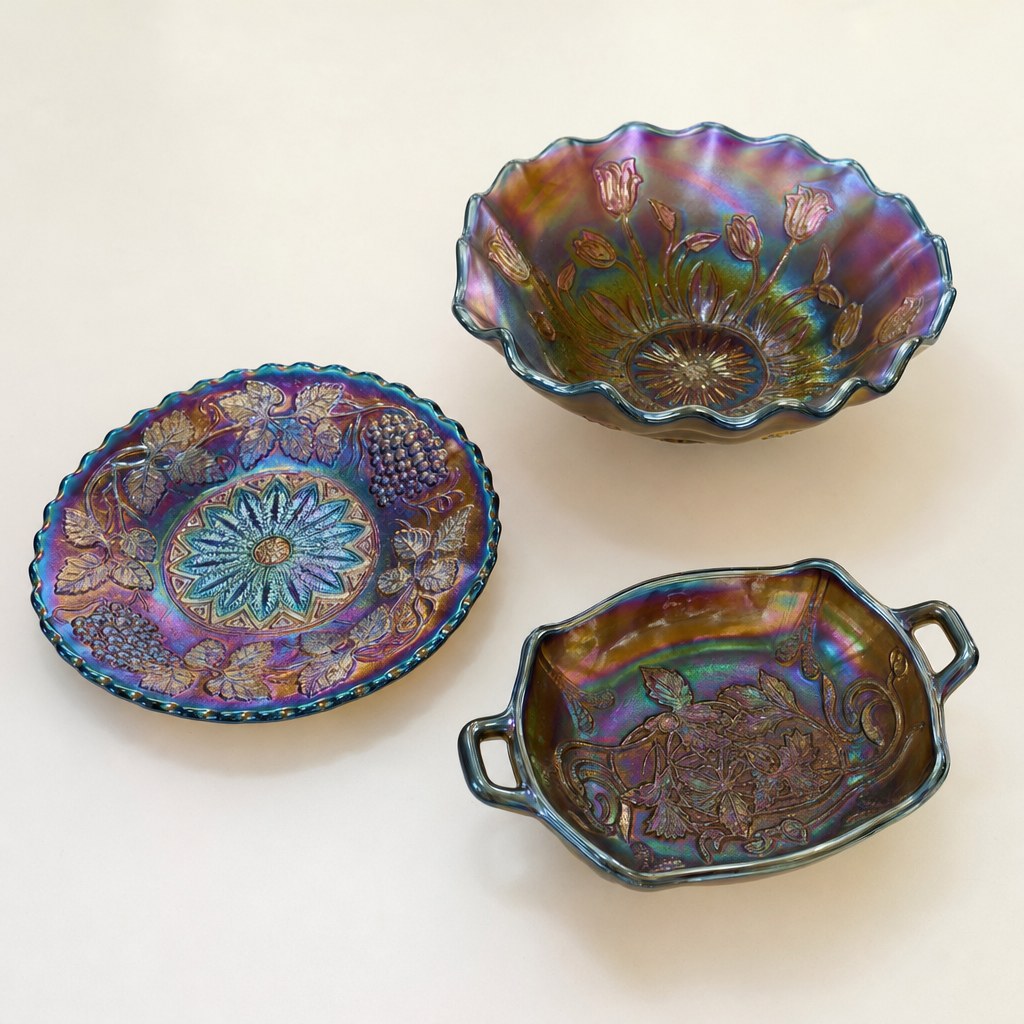 Three different shapes of iridescent Carnival glass, including a bowl, plate, and handled dish