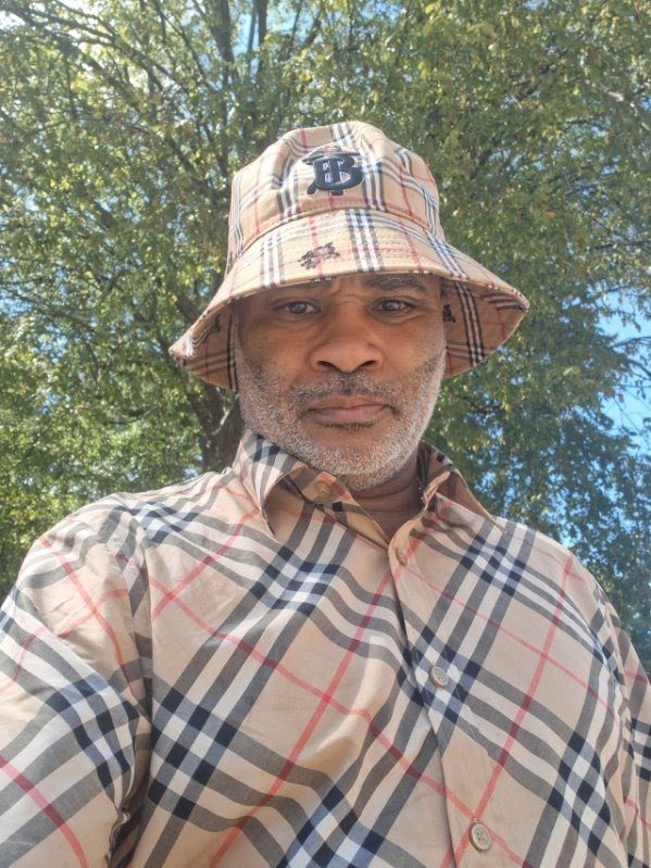 Lawrence McGriff in a plaid shirt and bucket hat outdoors