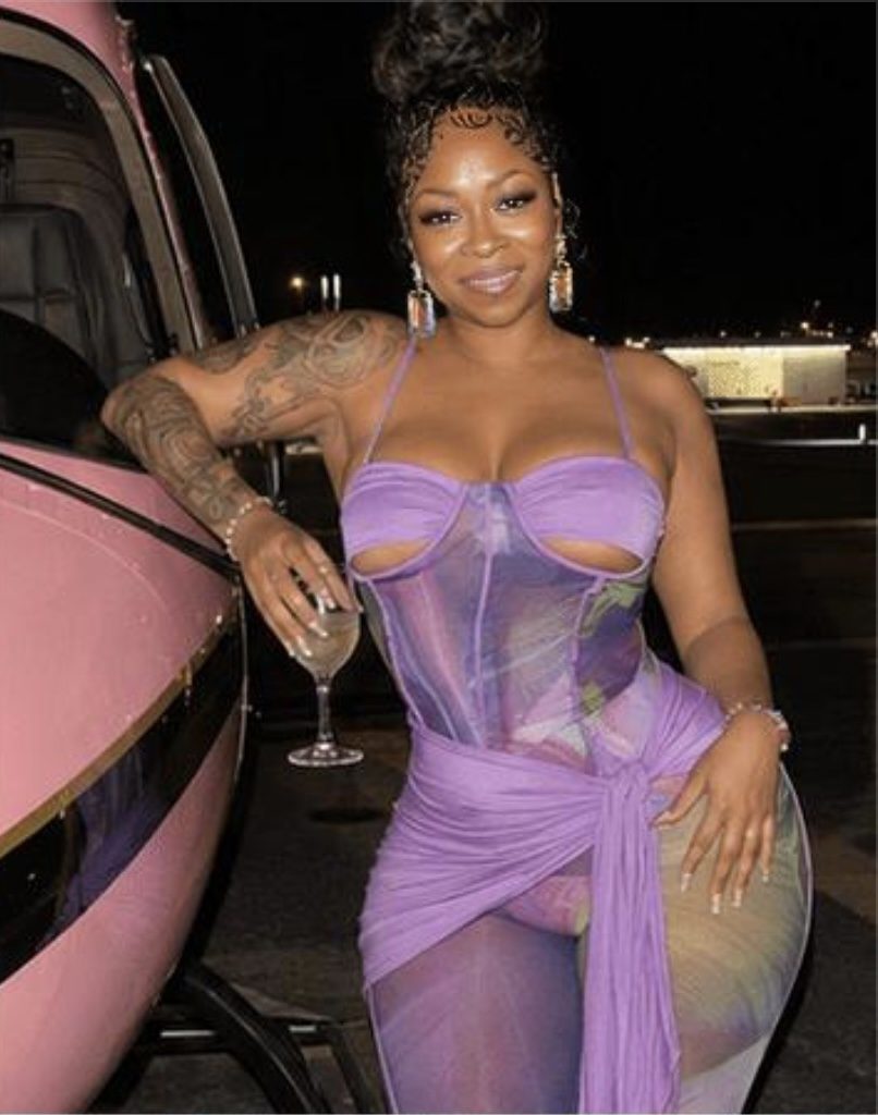 Station portrait in a lavender dress beside a pink vehicle