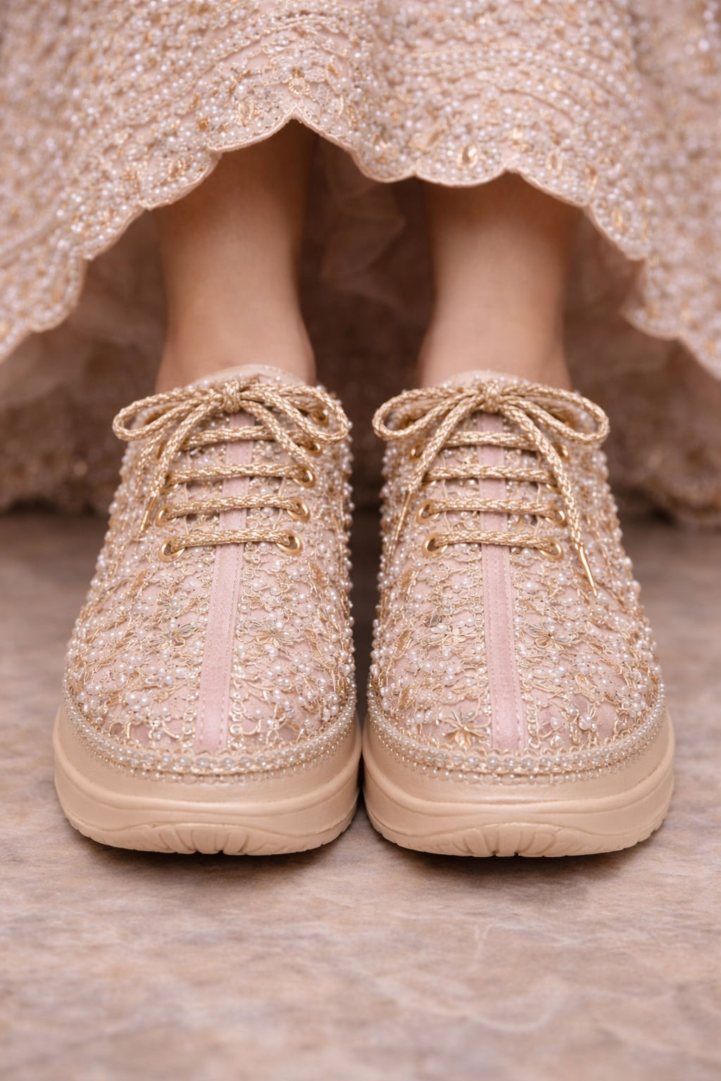 Bride wearing embellished ivory sneakers beneath an embroidered lehenga
