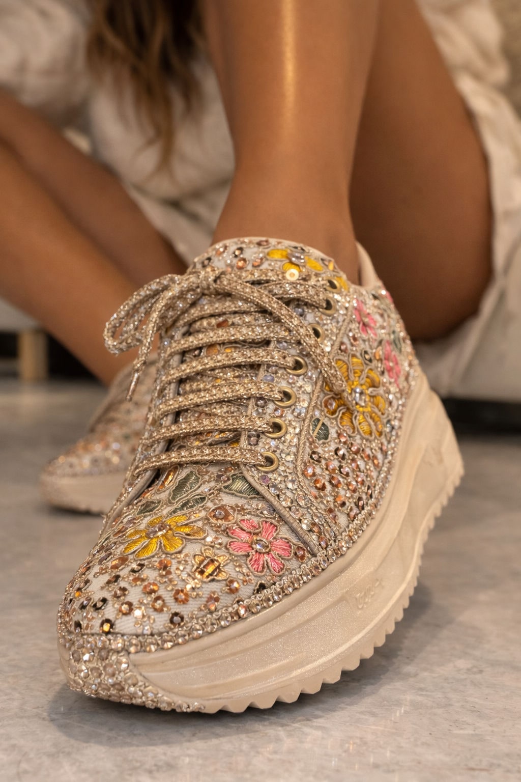 Embroidered ivory wedding sneaker with floral beadwork beneath a lehenga