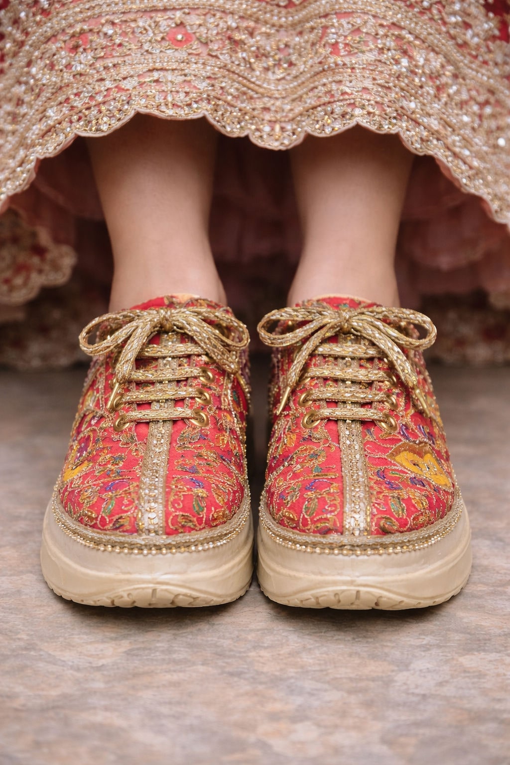 Pair of ivory embellished wedding sneakers beneath a beaded lehenga