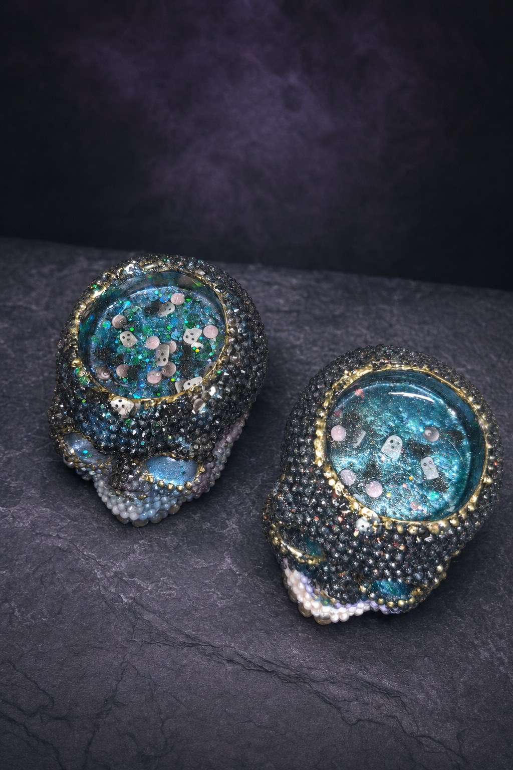 Handmade resin diamond skull candle holder pair viewed from above, showing the colorful tops