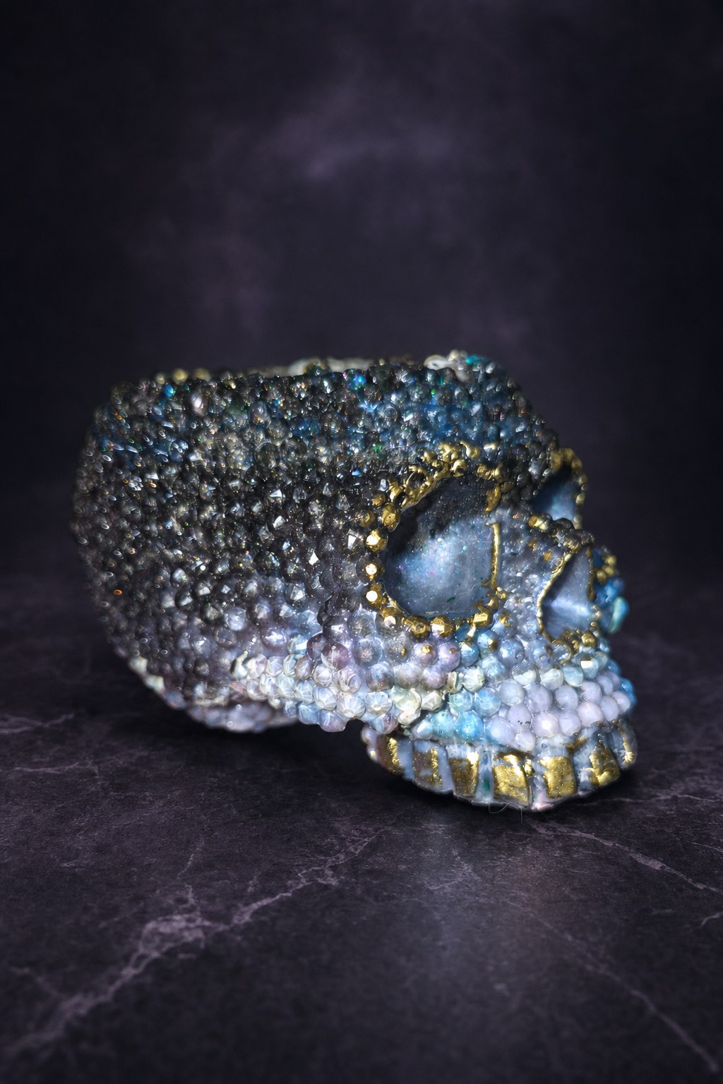 Side view of a resin diamond skull candle holder with gold details