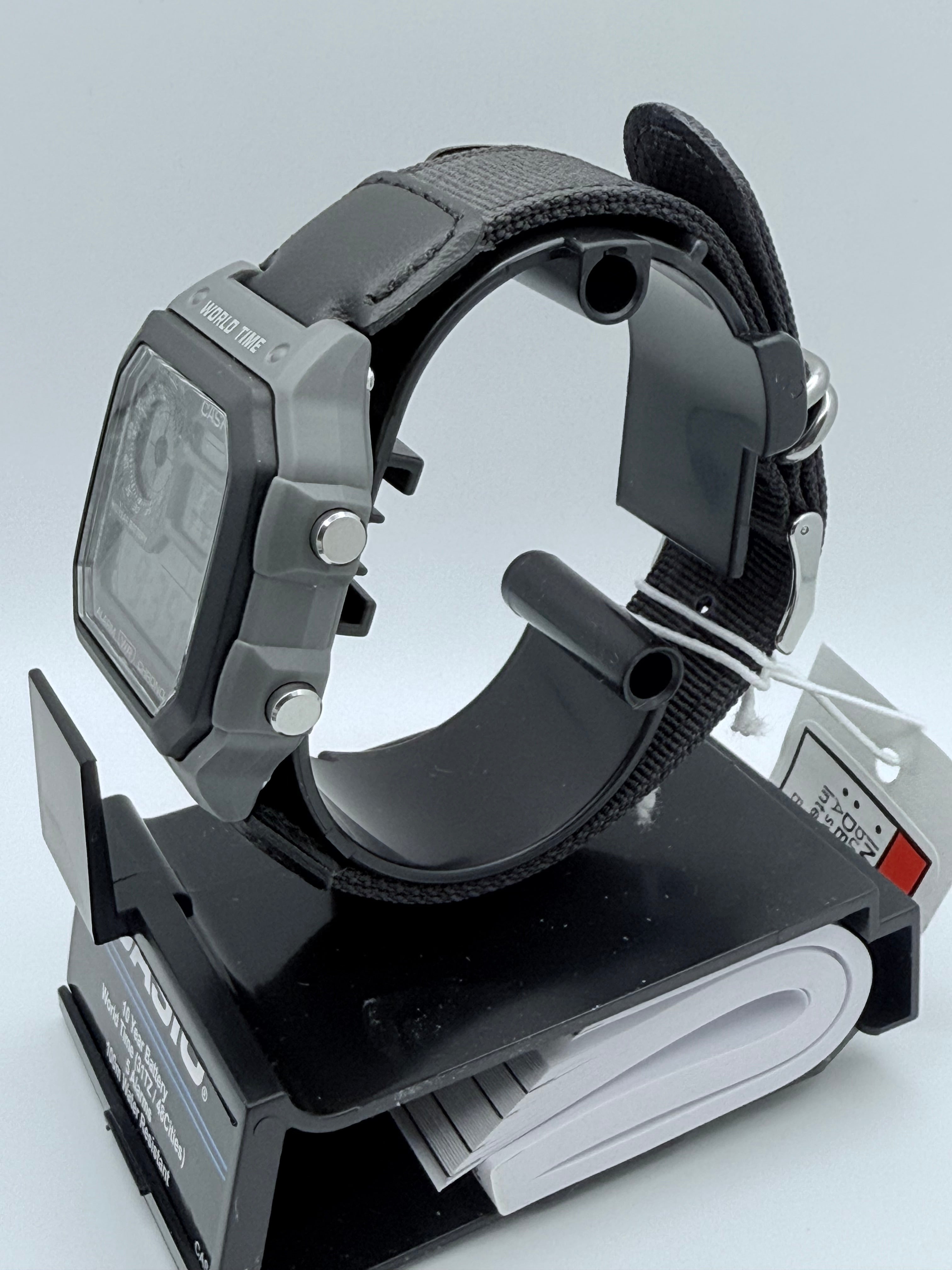 Close side view of the Casio AE1200, its buttons, and dark woven strap