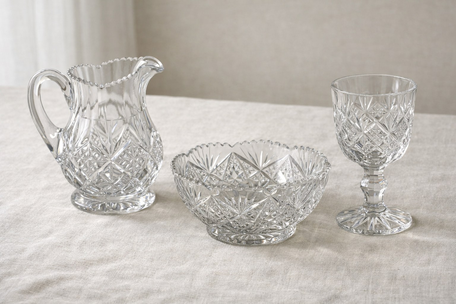 Clear cut-glass pitcher, bowl, and goblet arranged for close inspection