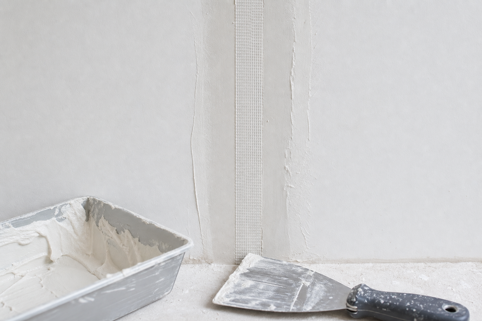 Paper drywall tape embedded in joint compound over a repaired wall seam