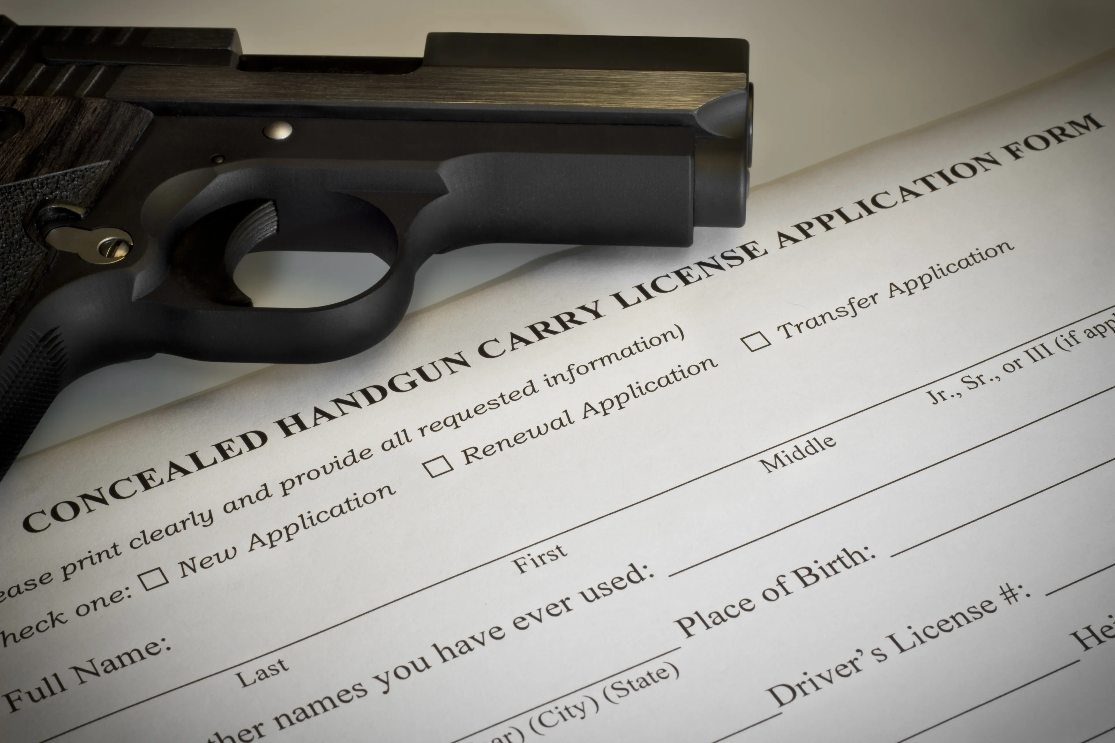 Concealed carry permit renewal application form beside a handgun