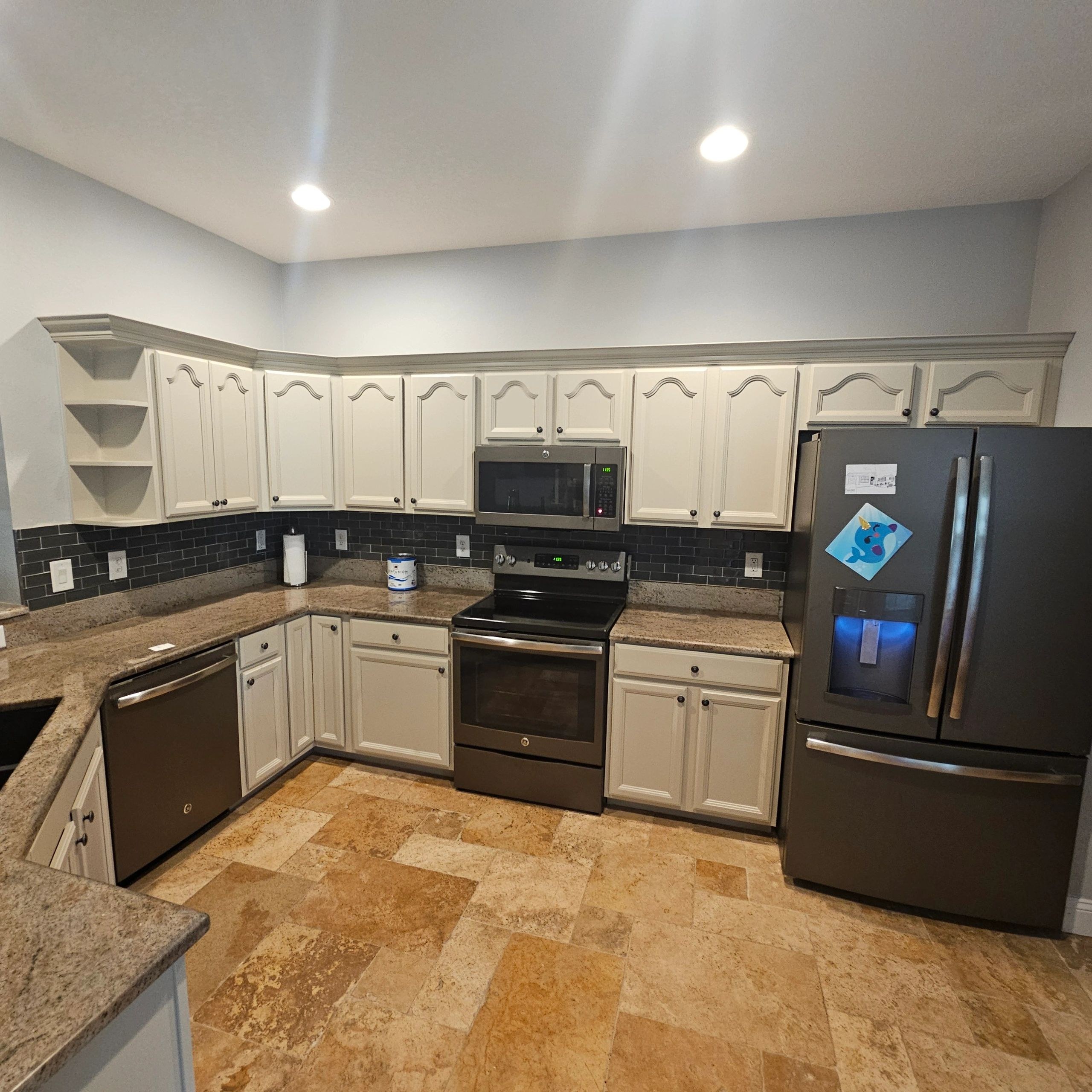 Wide kitchen view with painted cabinets, range and refrigerator
