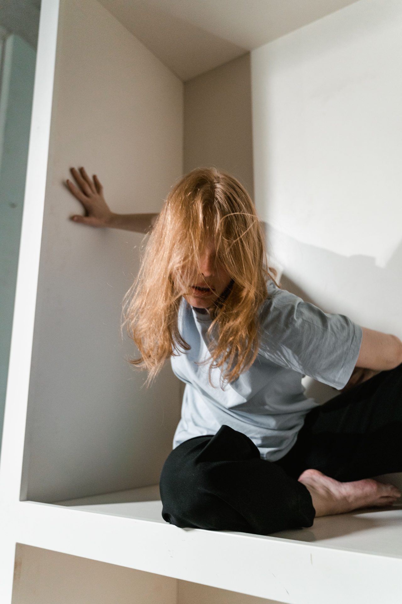 Woman sitting in a confined space with her hand against the wall