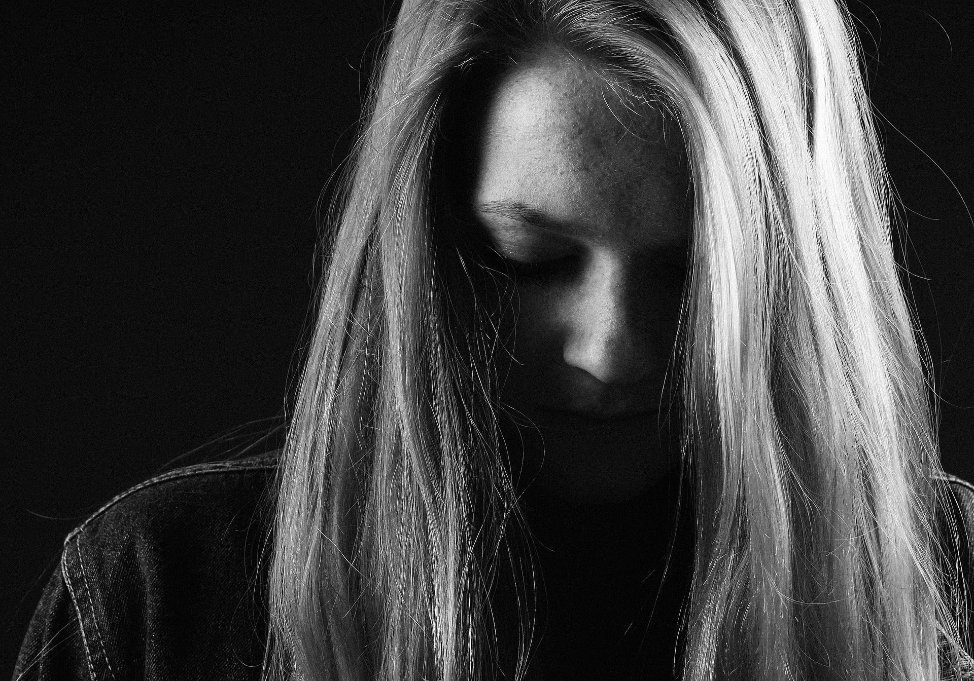 Woman with long hair looking down thoughtfully