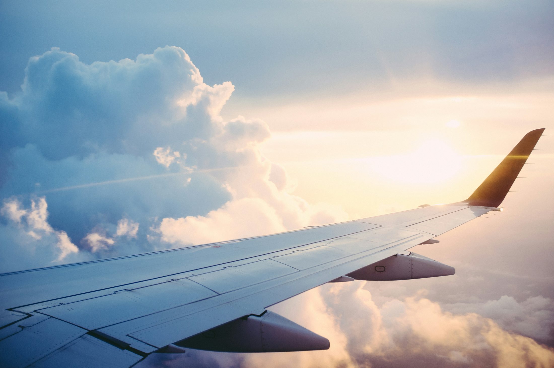 Airplane wing above the clouds in warm sunlight
