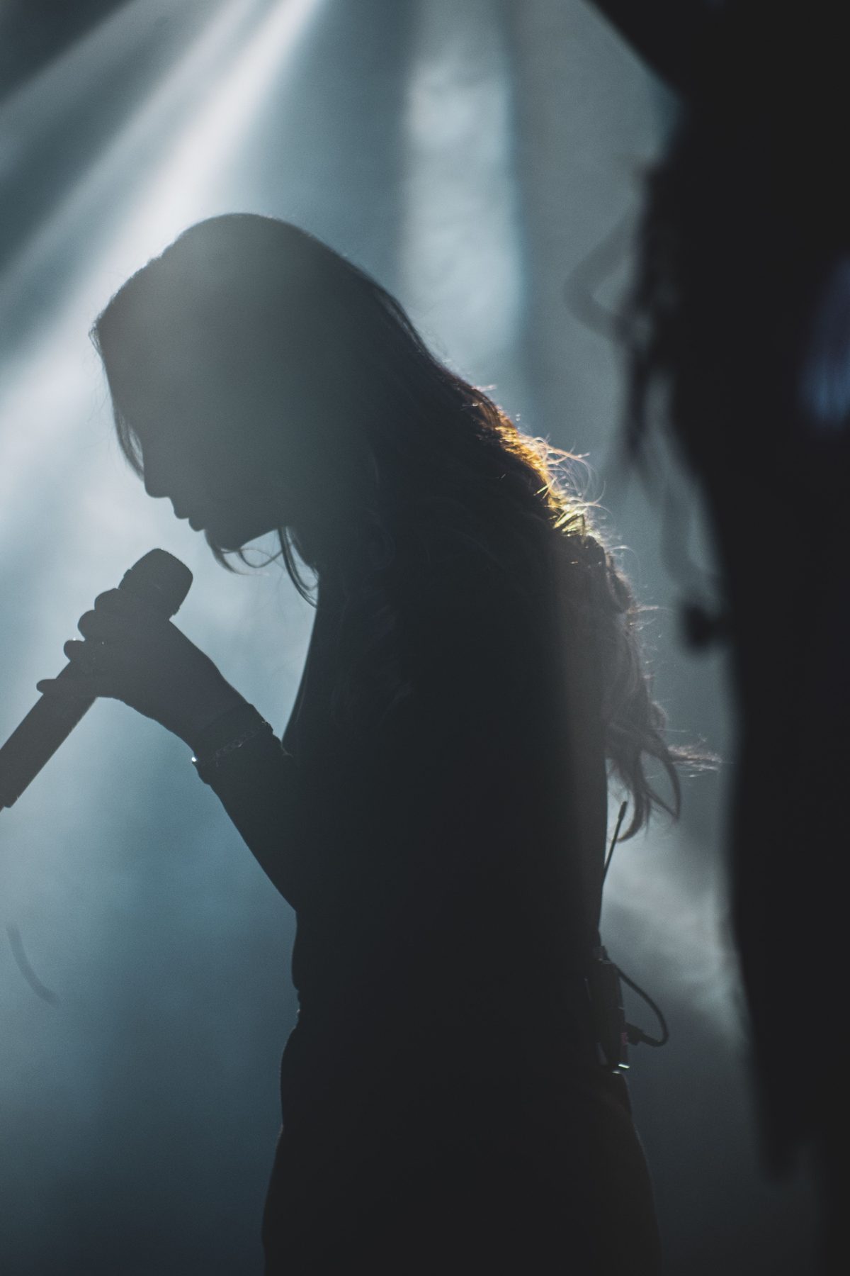 Singer holding a microphone in atmospheric stage lighting
