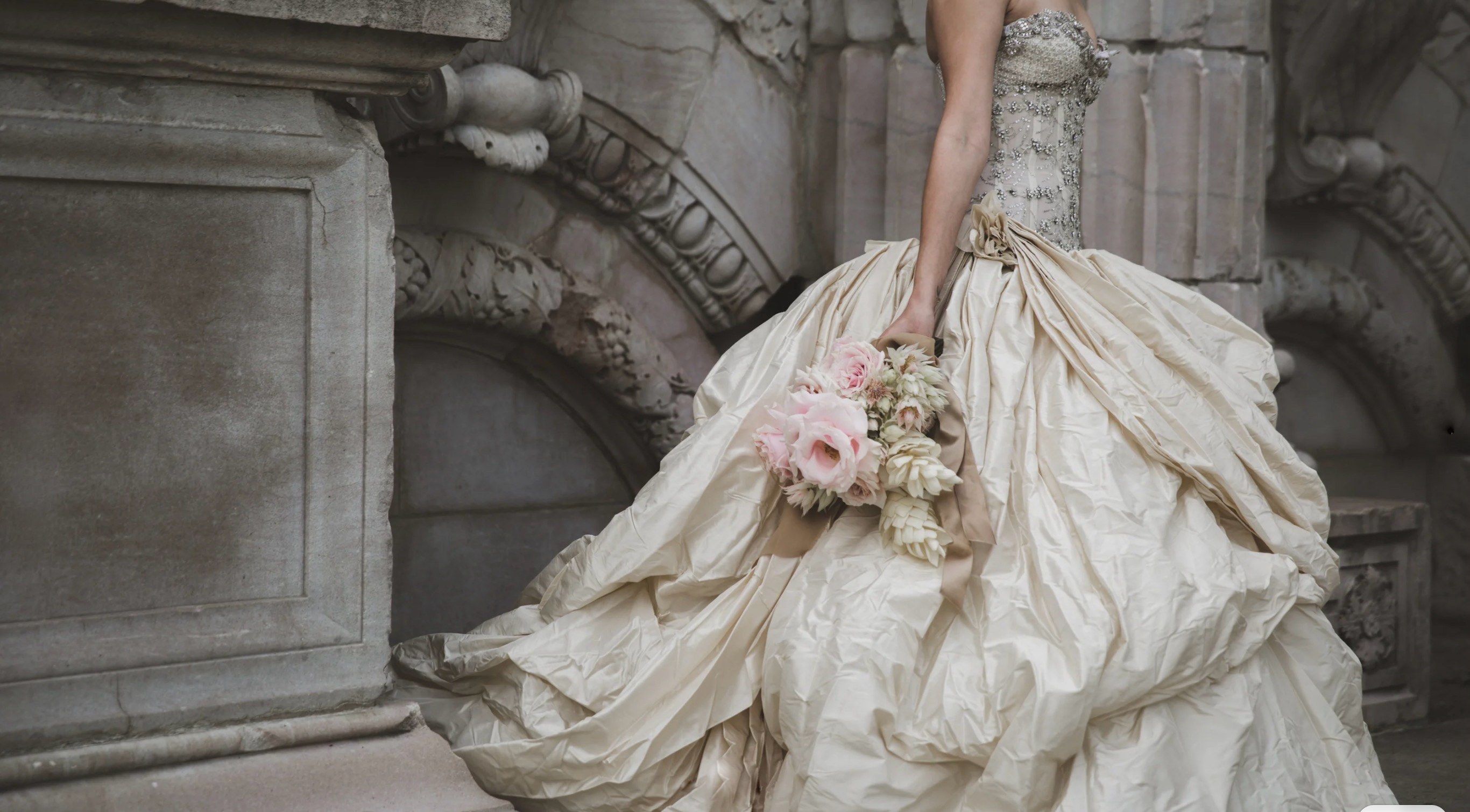 Bridal gown with antique-inspired beading and a soft pink bouquet
