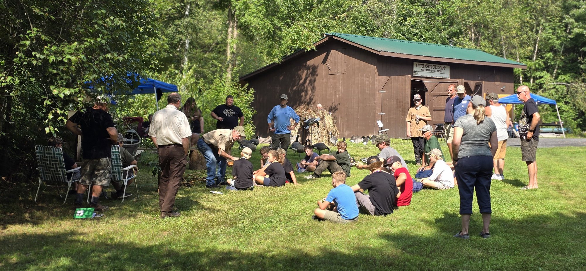 Adults and young people gathered on a lawn for an outdoor lesson