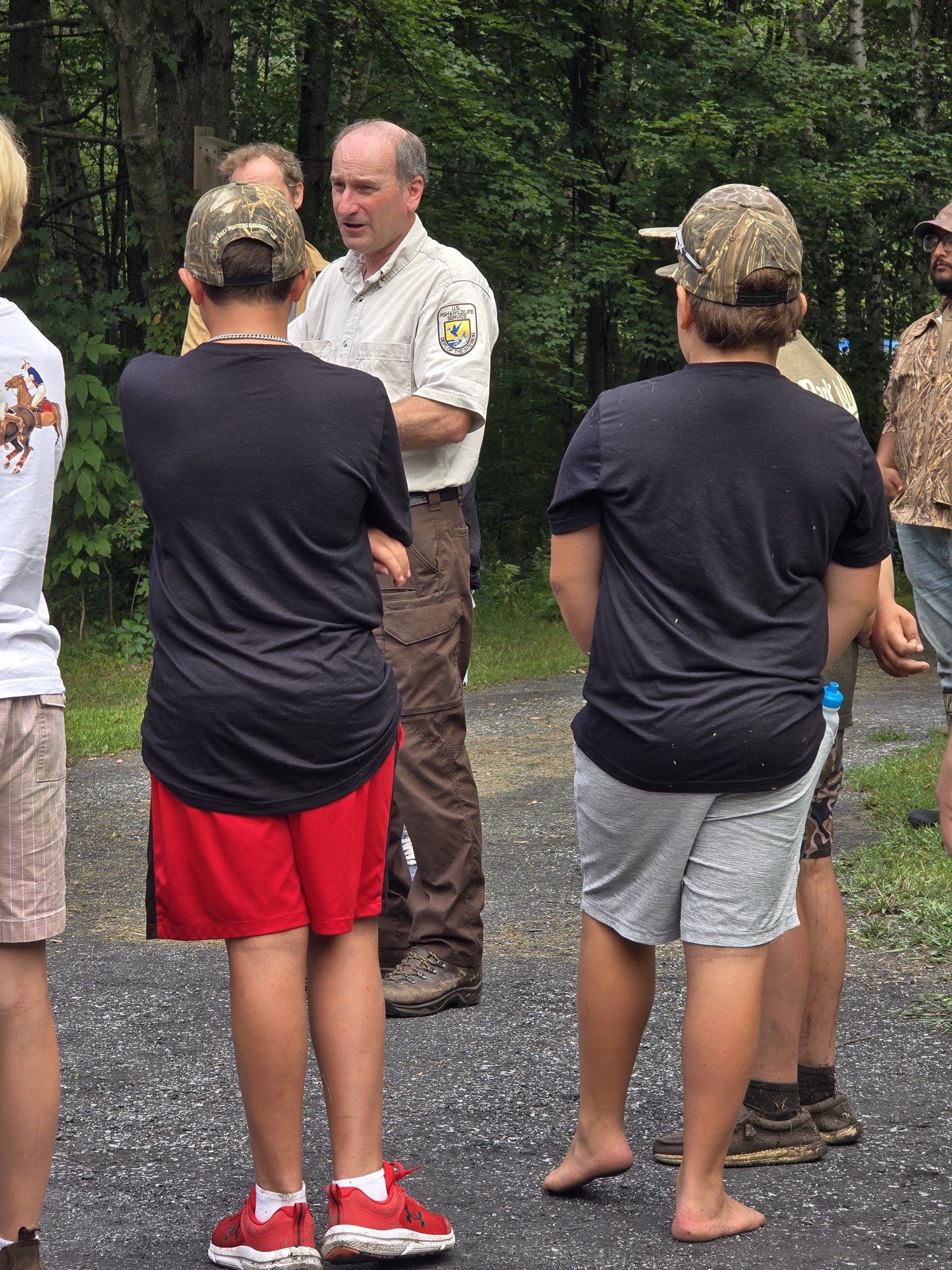 An adult talking with young participants outdoors
