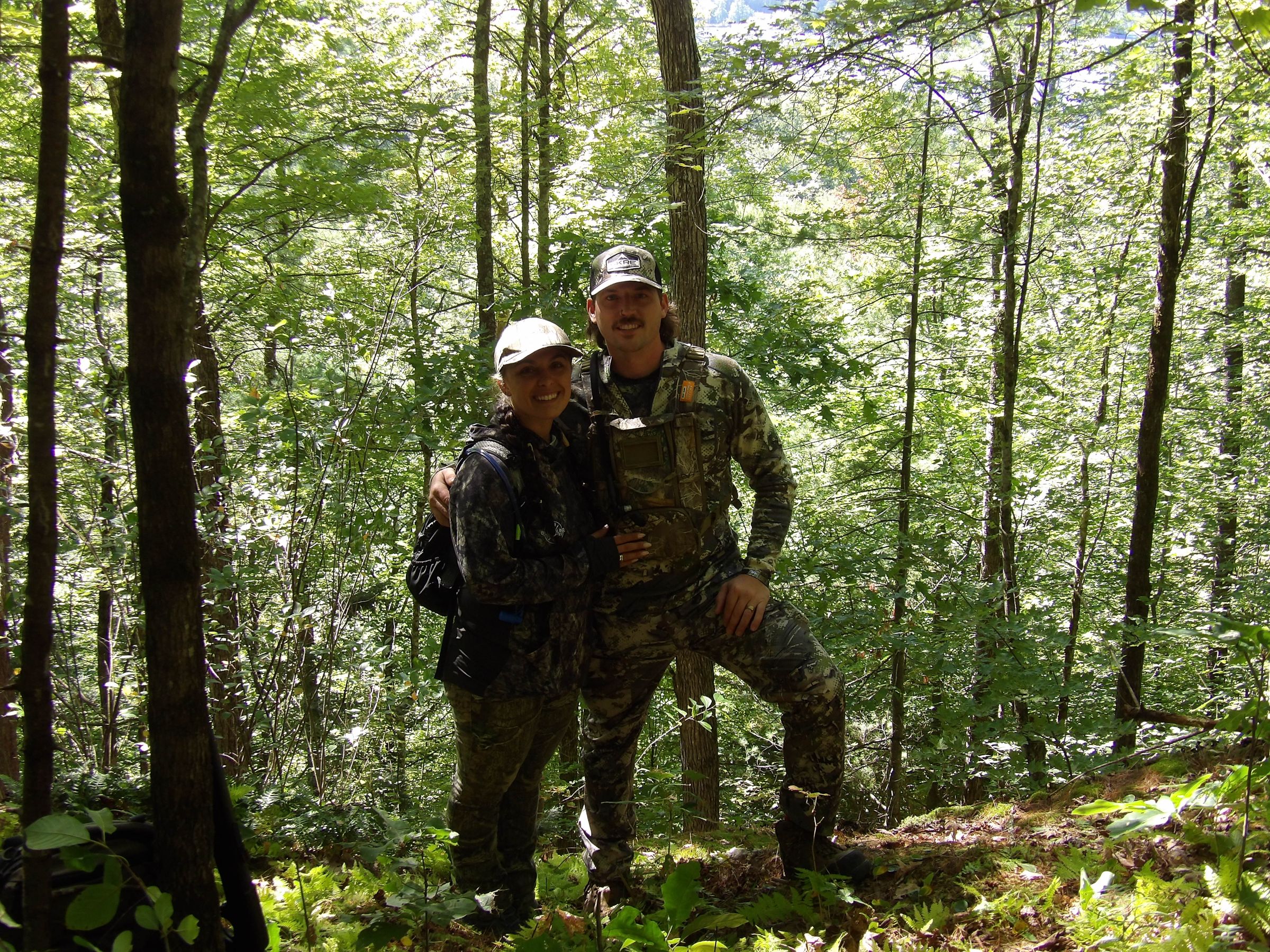 A couple in camouflage together in a sunlit forest