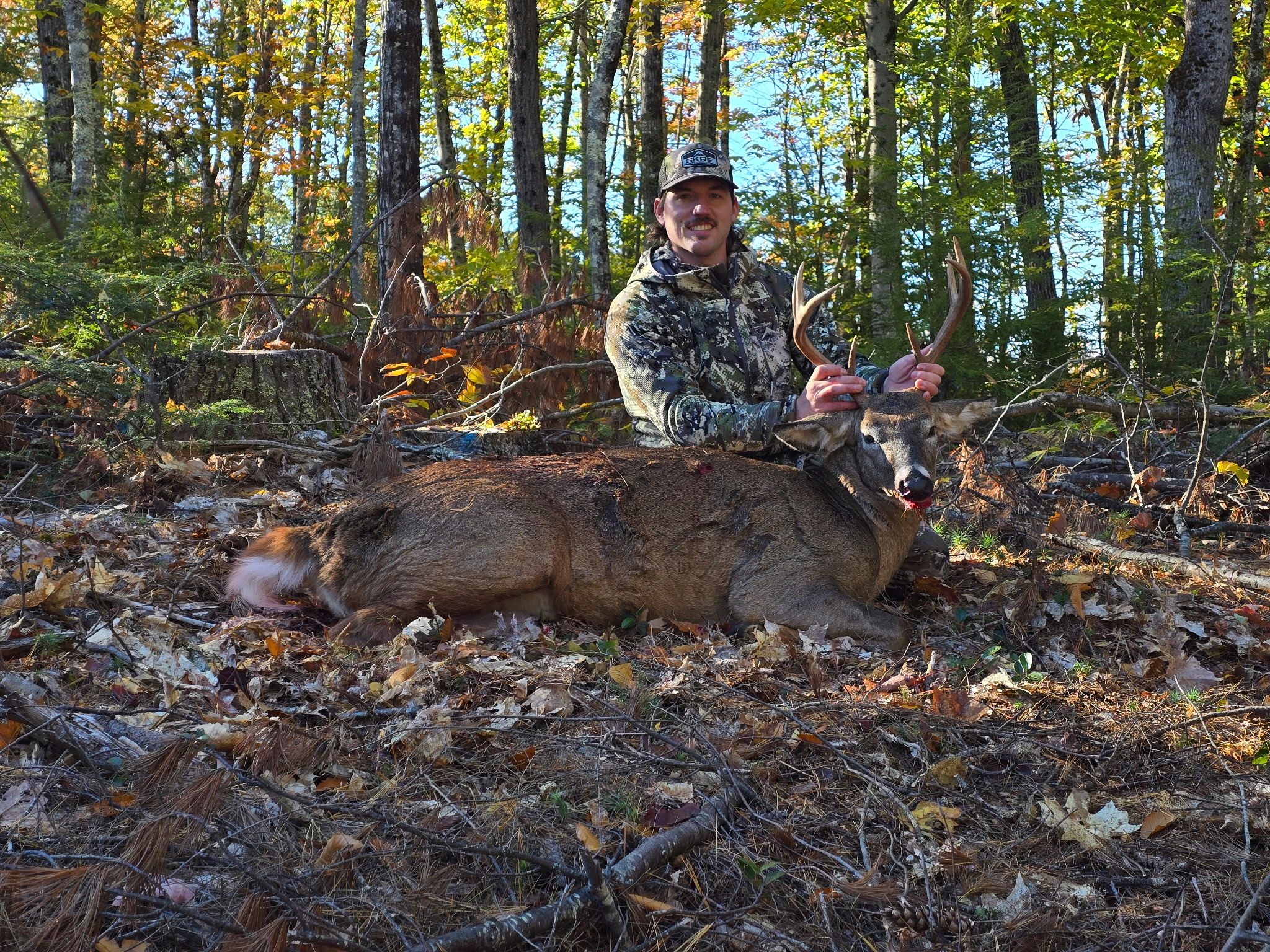 A hunter with a harvested buck in the autumn woods