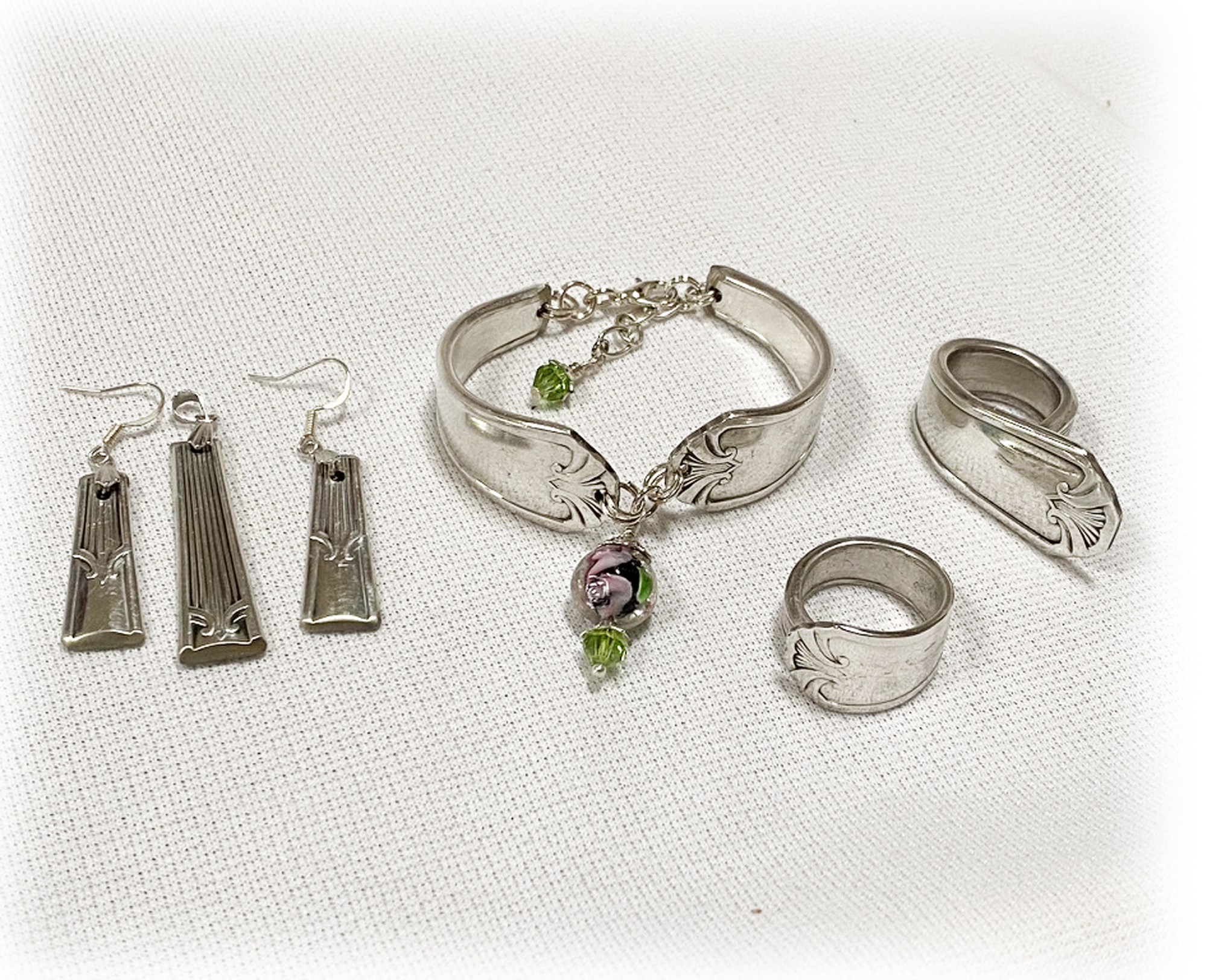 Custom family heirloom jewelry, including earrings, bracelet, and rings, arranged on linen