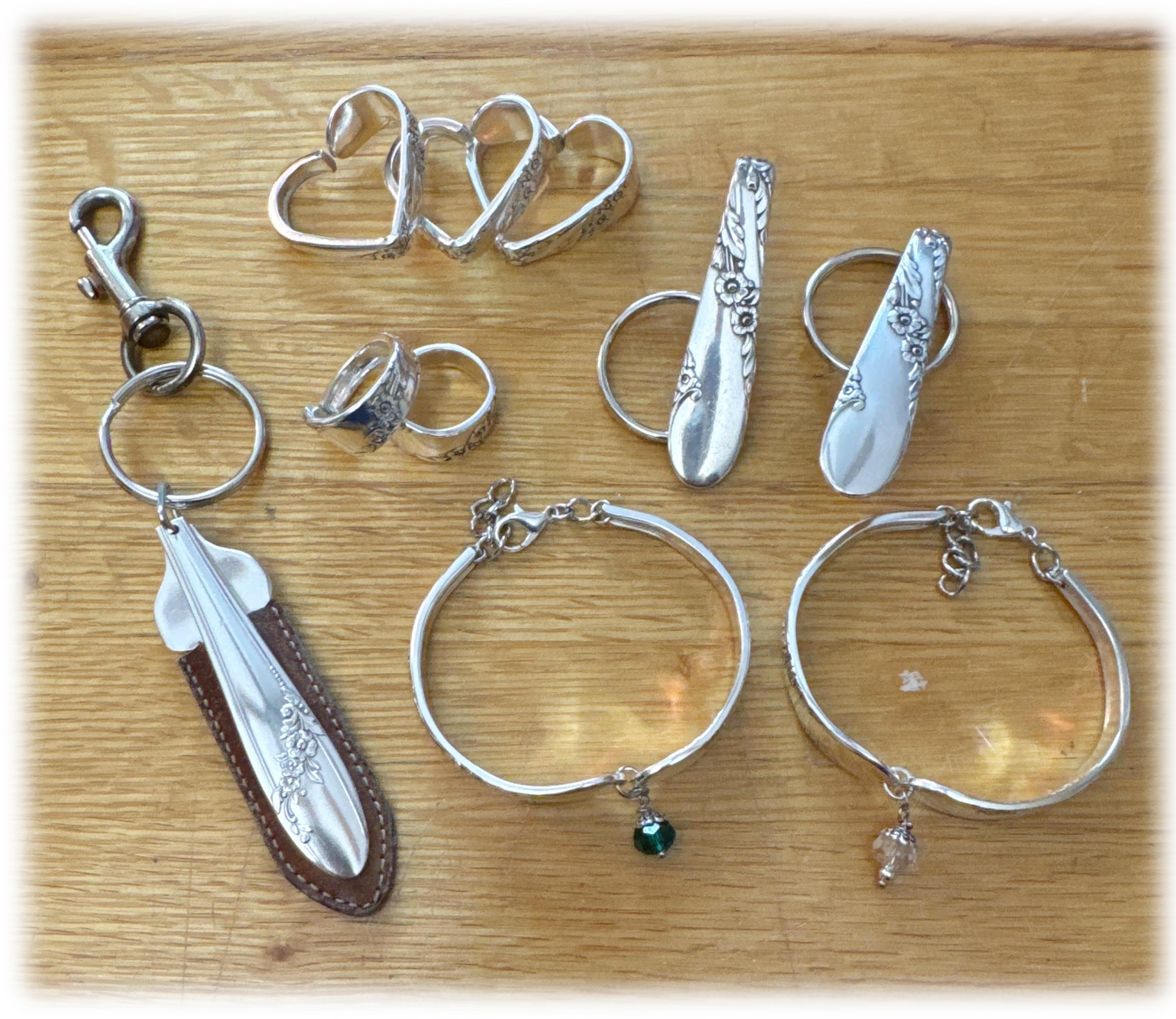 Custom jewelry and keyring made from inherited silverware, arranged on a wooden table