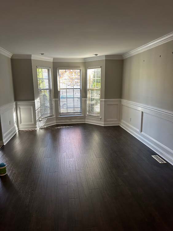 Light neutral painted bedroom with white trim and dark flooring