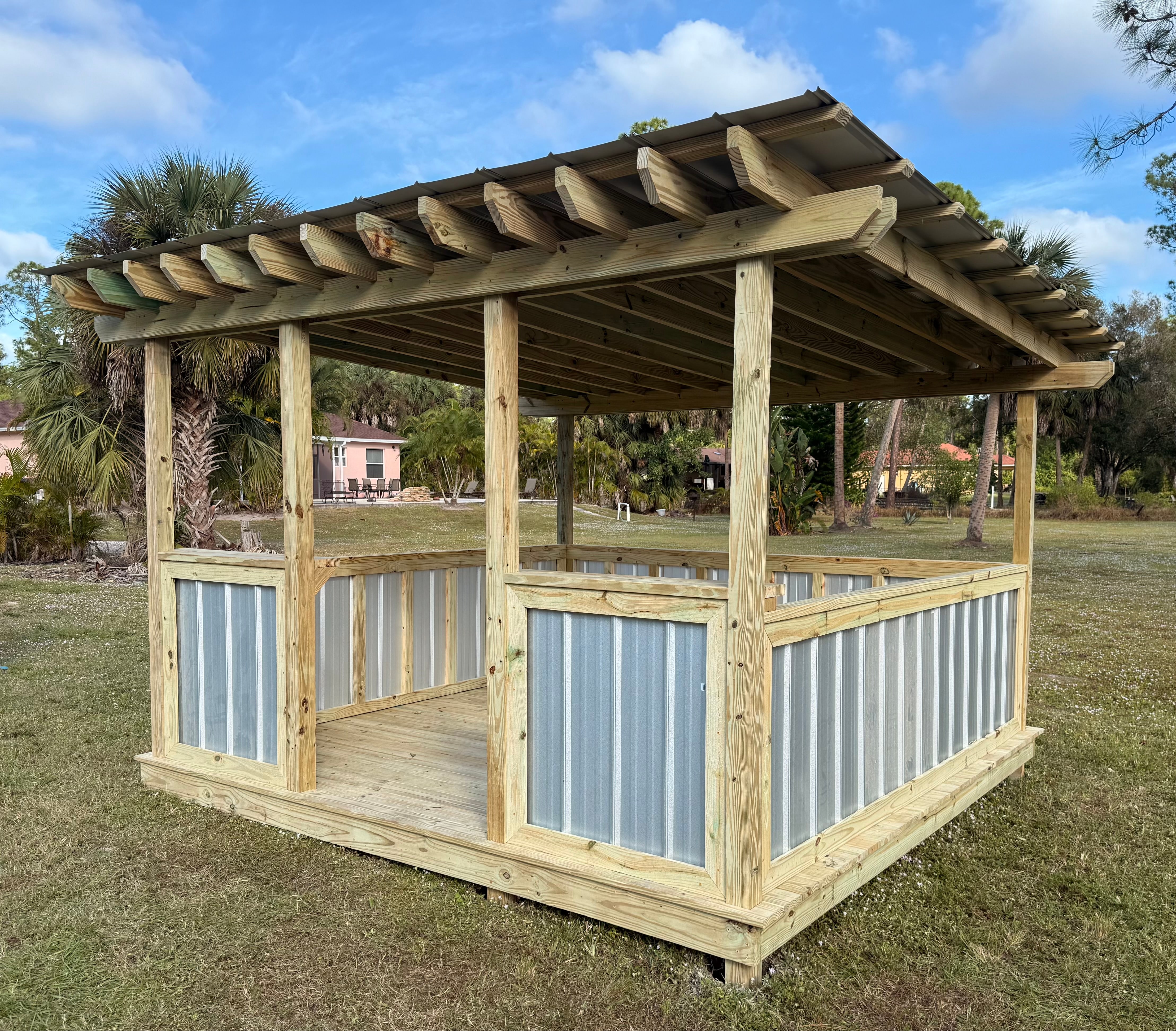 Open-air wood grill hut with metal roof and side panels