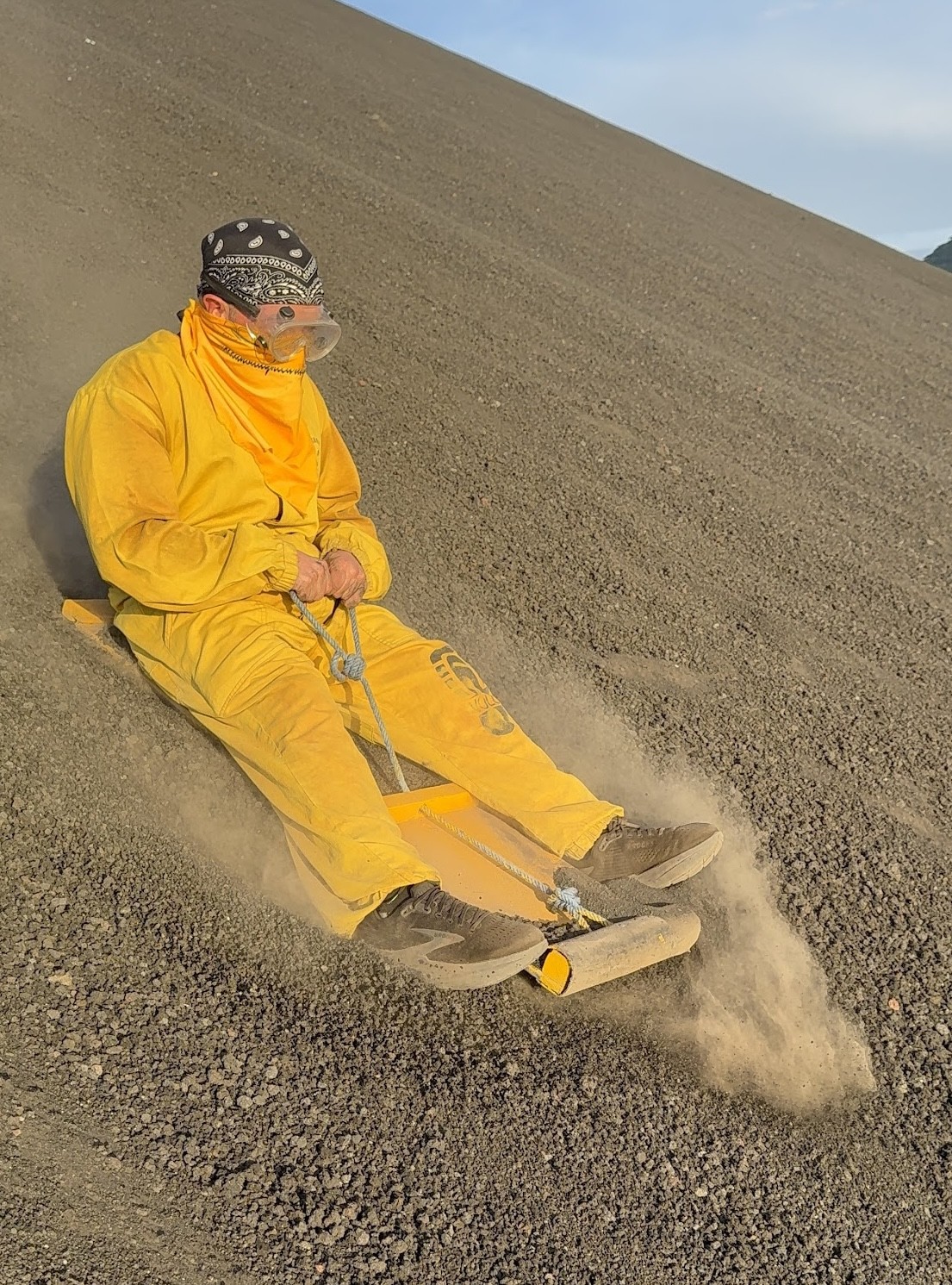Volcano boarder in a yellow jumpsuit descending Cerro Negro in Nicaragua