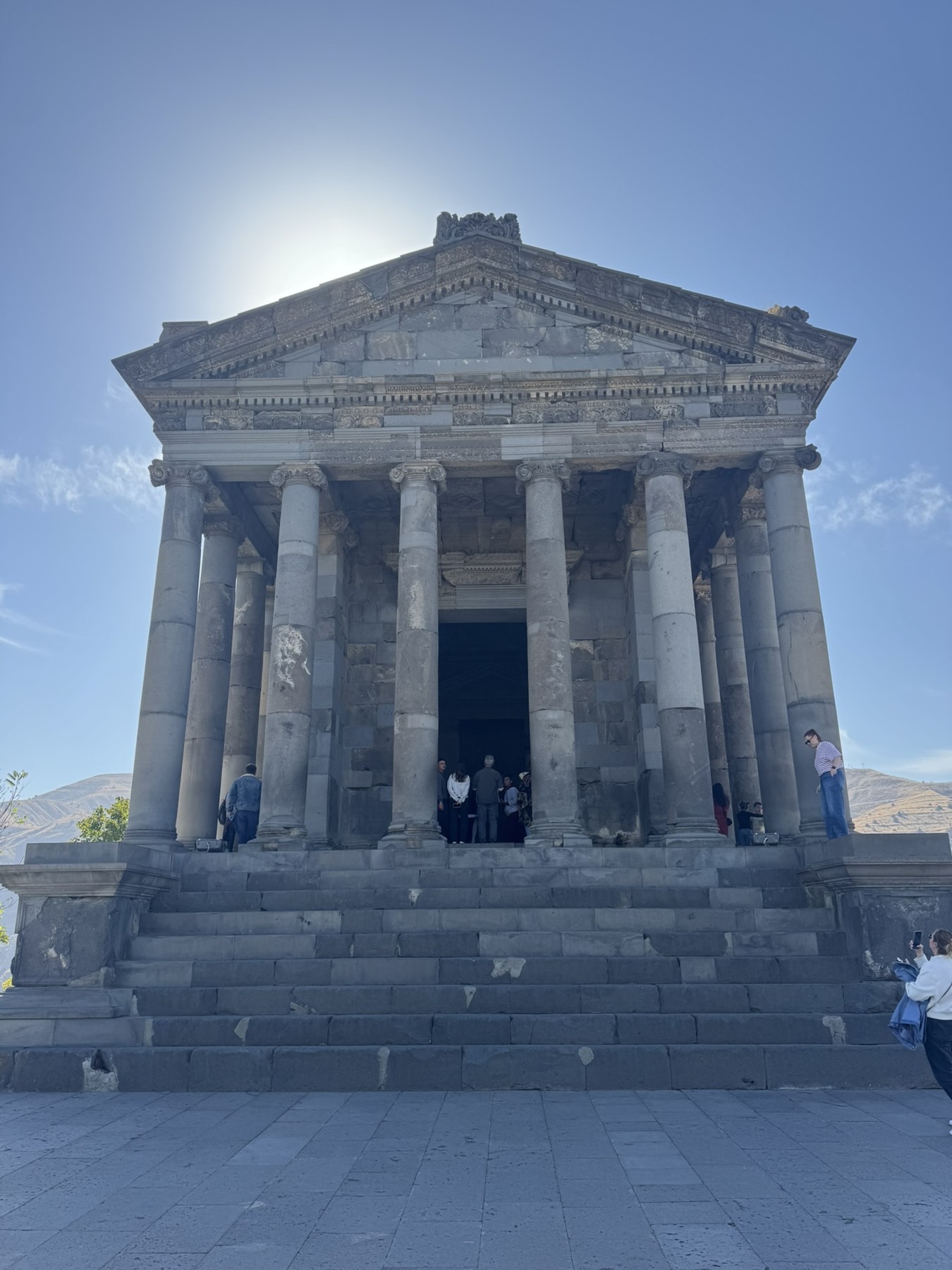 The columned facade and steps of Garni Temple in the sunlight.
