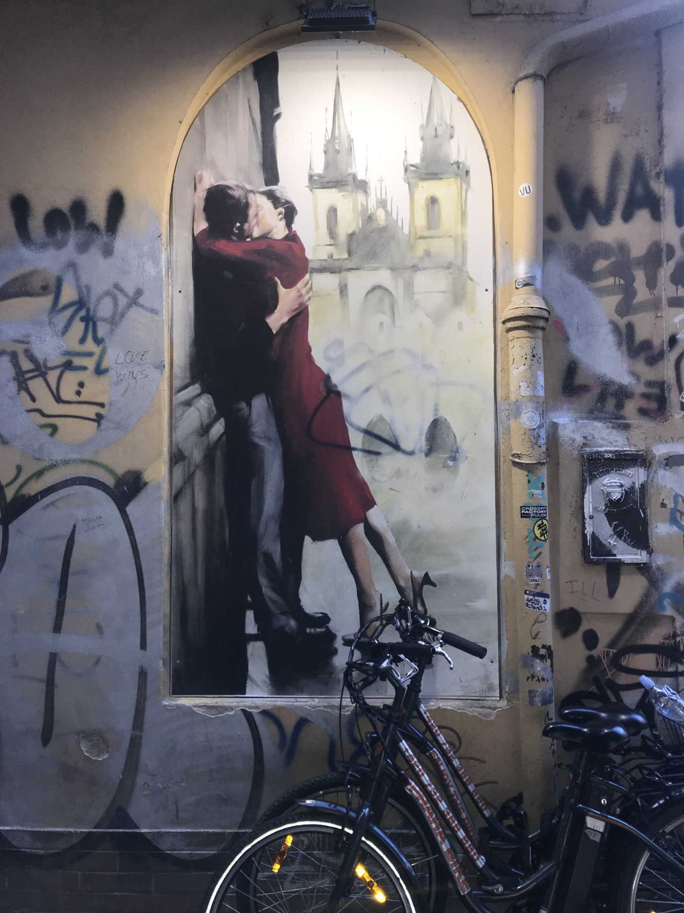Street art beside a bicycle in a Prague passageway.