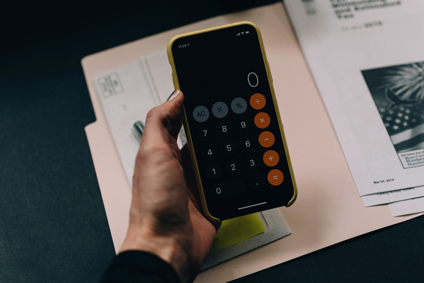 Business owner using a calculator while reviewing paperwork